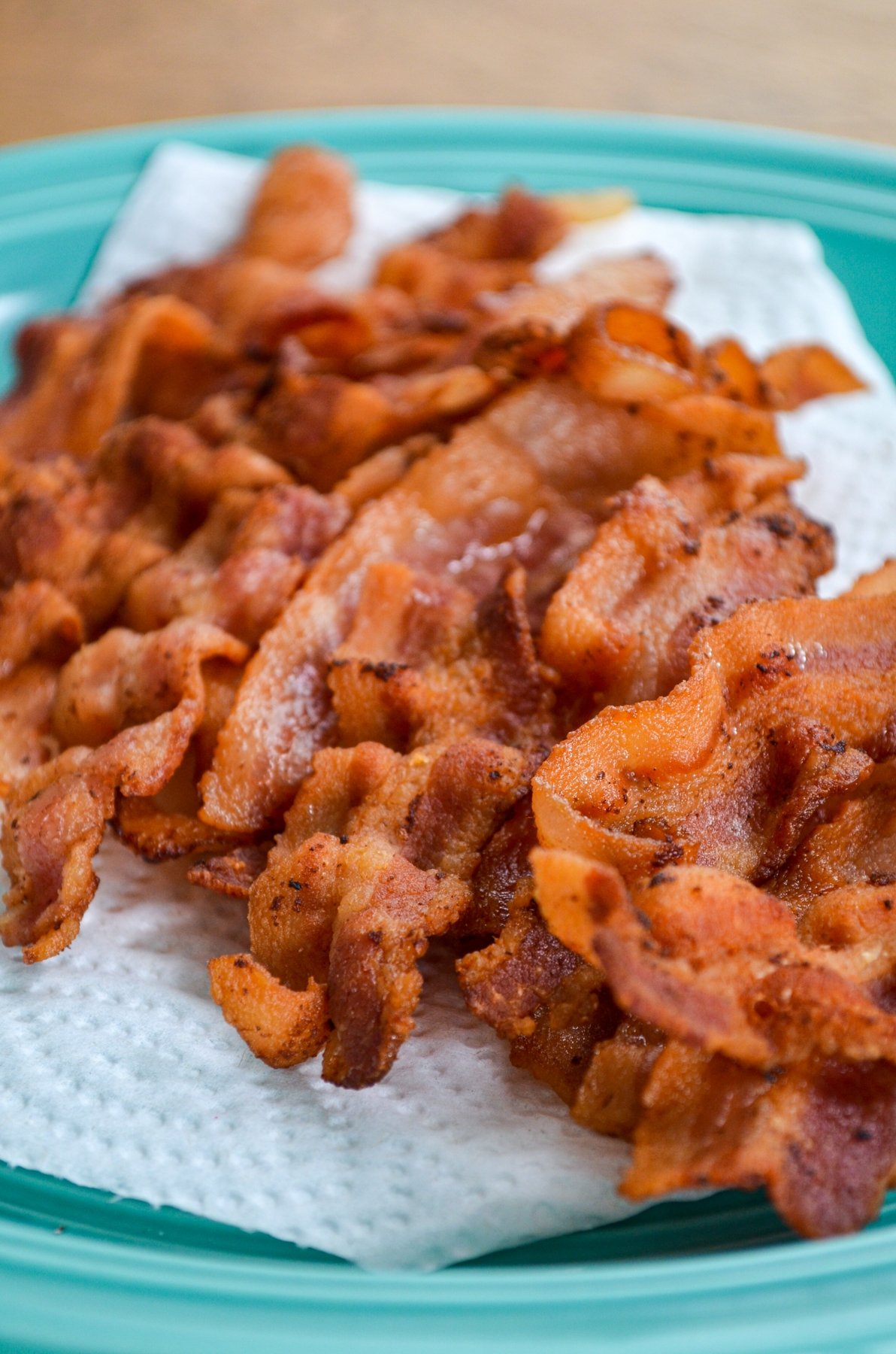 Instant Pot Bacon Slices, crispy and draining on a paper towel lined plate.