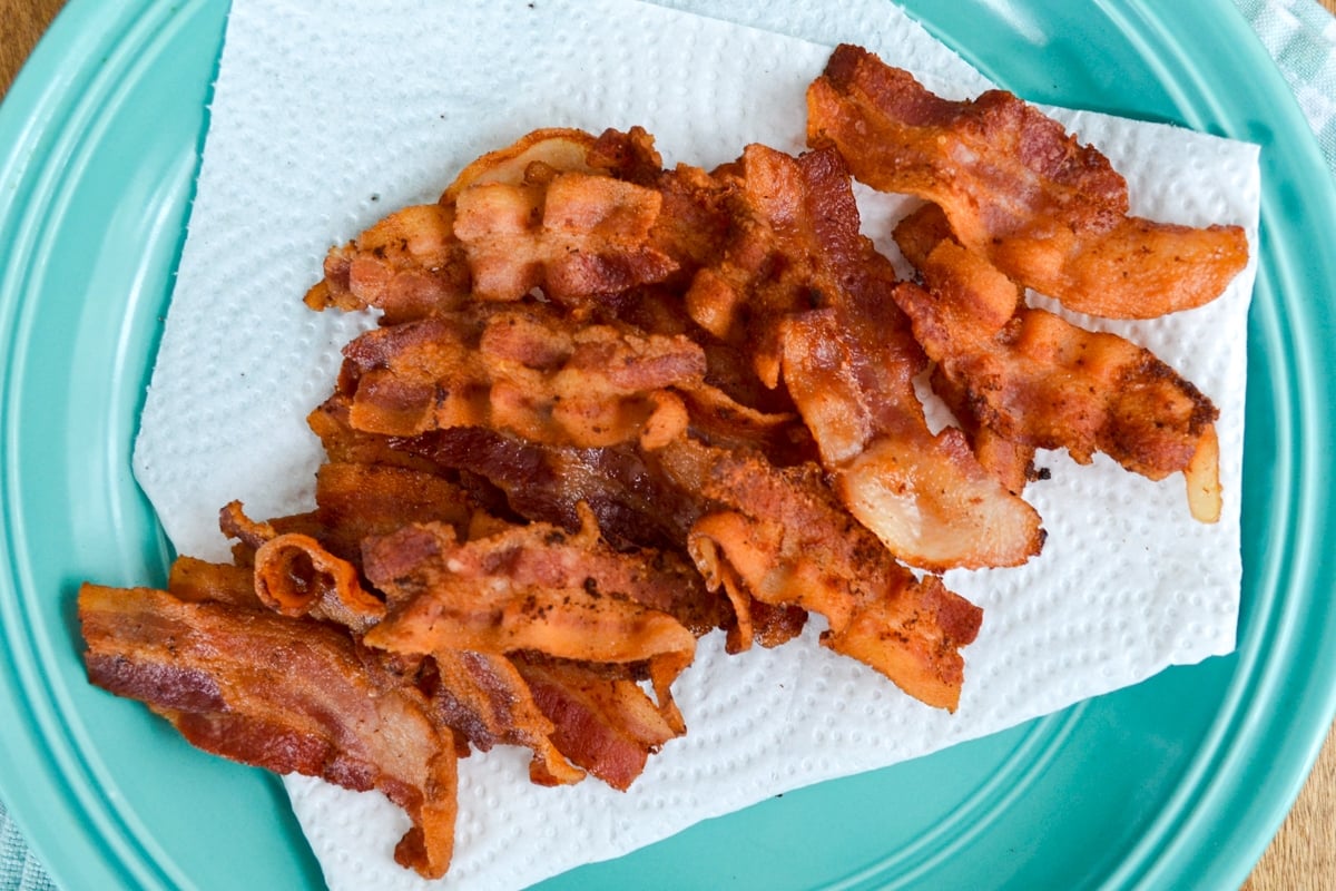 Cooked bacon slices on a paper towel lined plate. 
