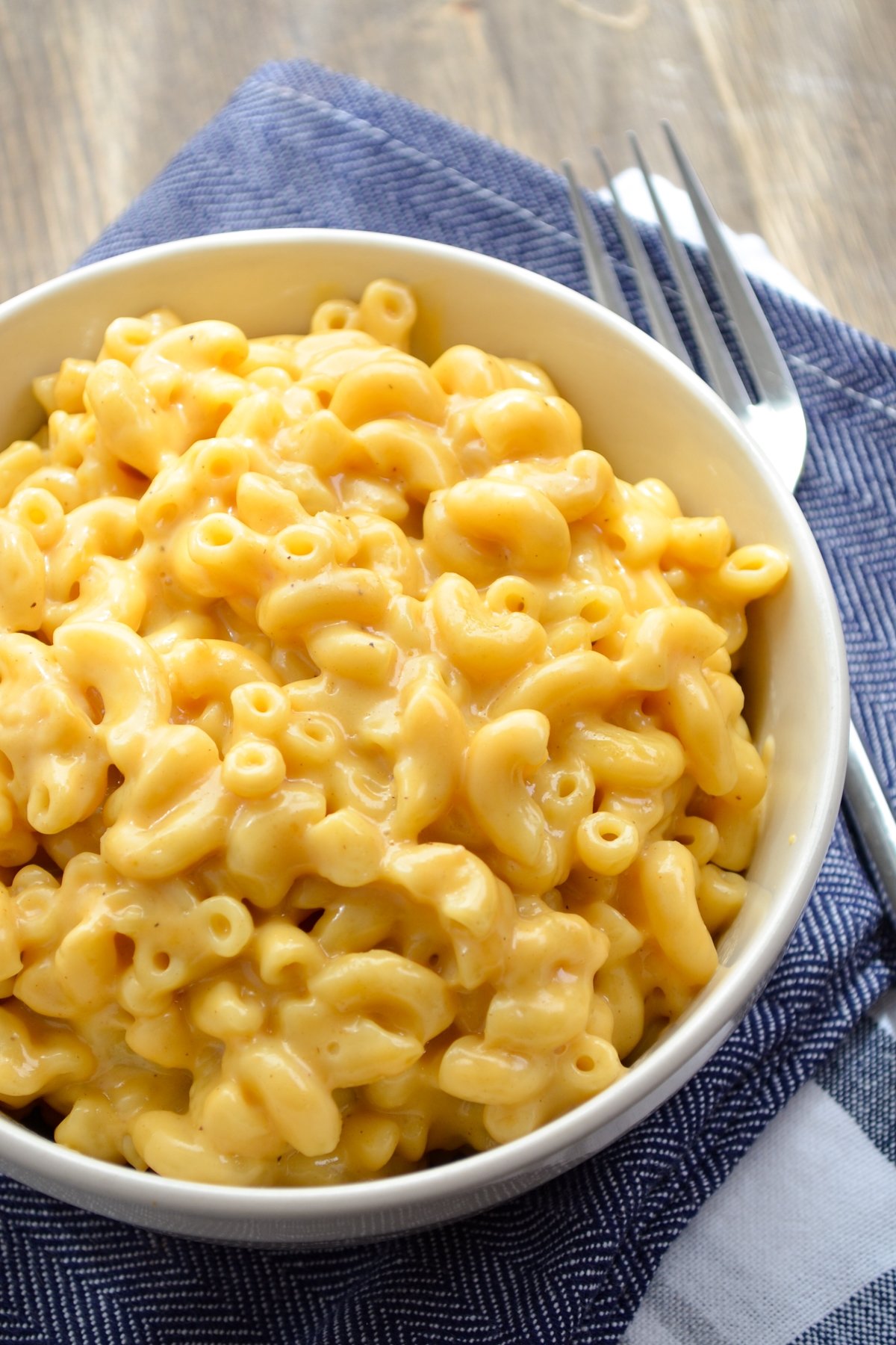 A bowl of macaroni and cheese, on a blue napkin.