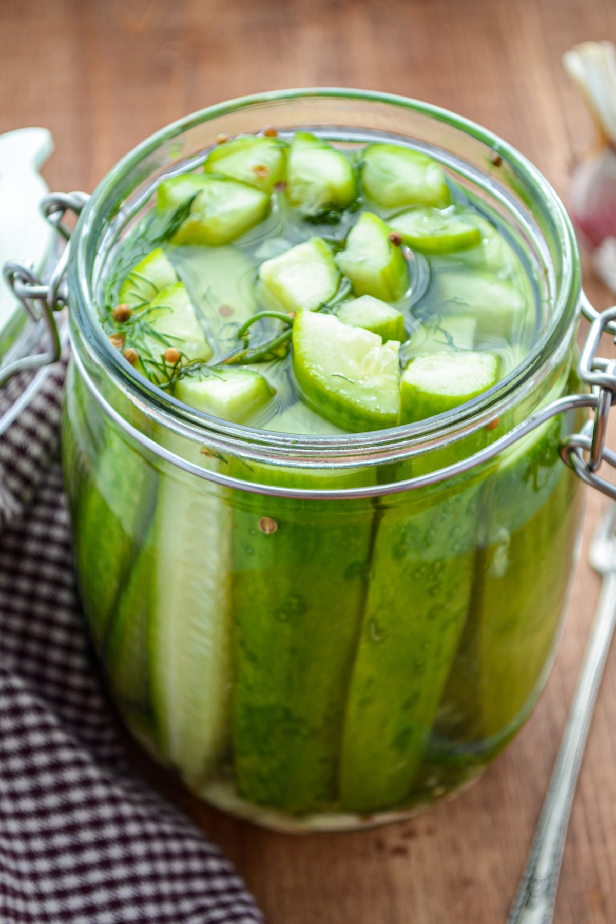 A jar of refrigerator pickles, resting alongside a gingham napkin.