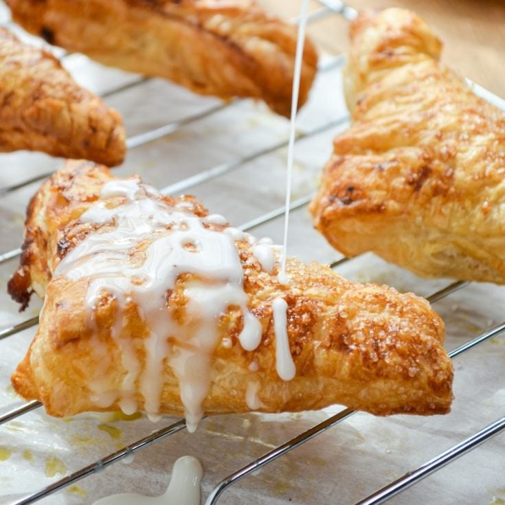 An apple turnover, being drizzled with a simple glaze.