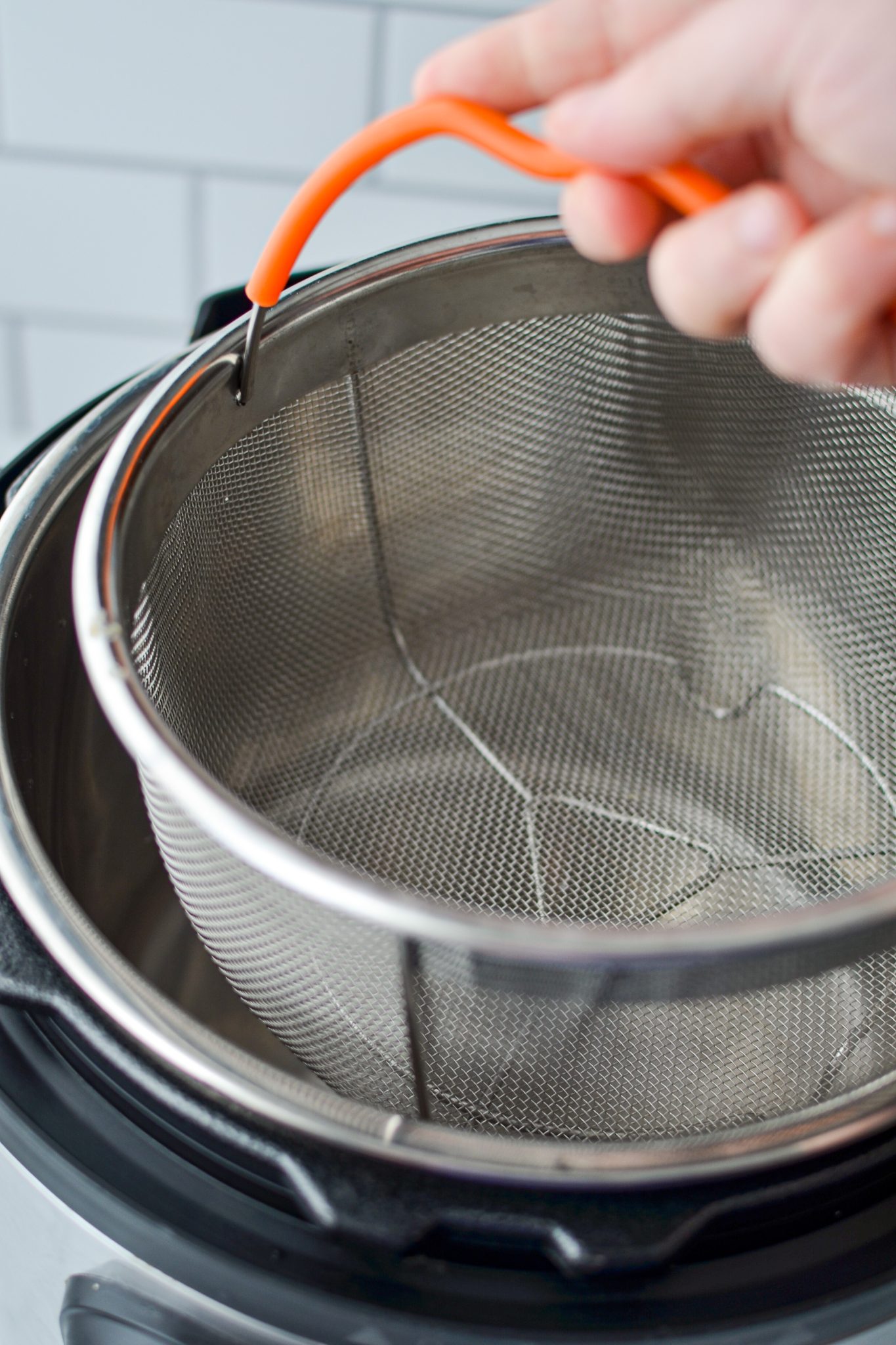 Lowering a steamer basket into the insert of an Instant Pot.
