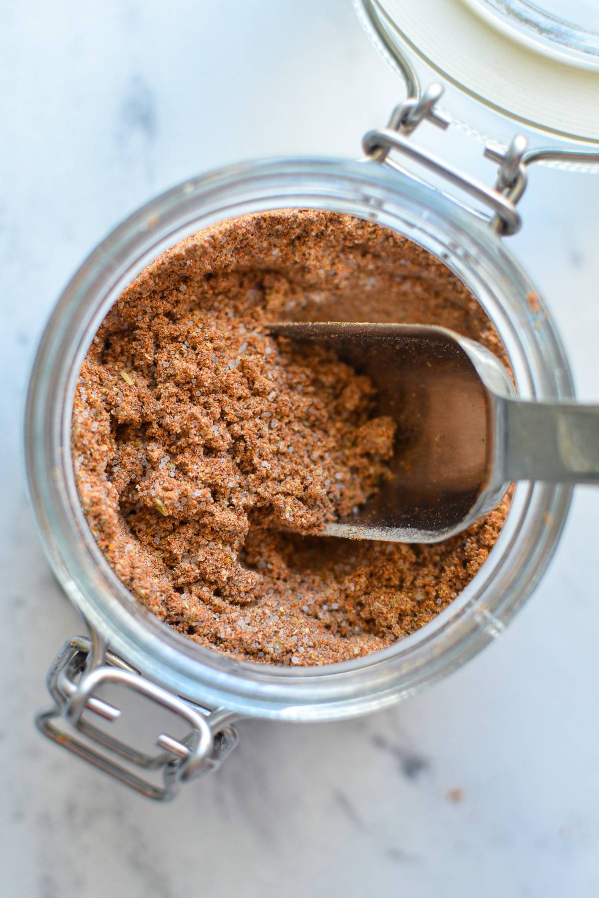 An overhead shot of a jar of taco seasoning with a spoon inside. 