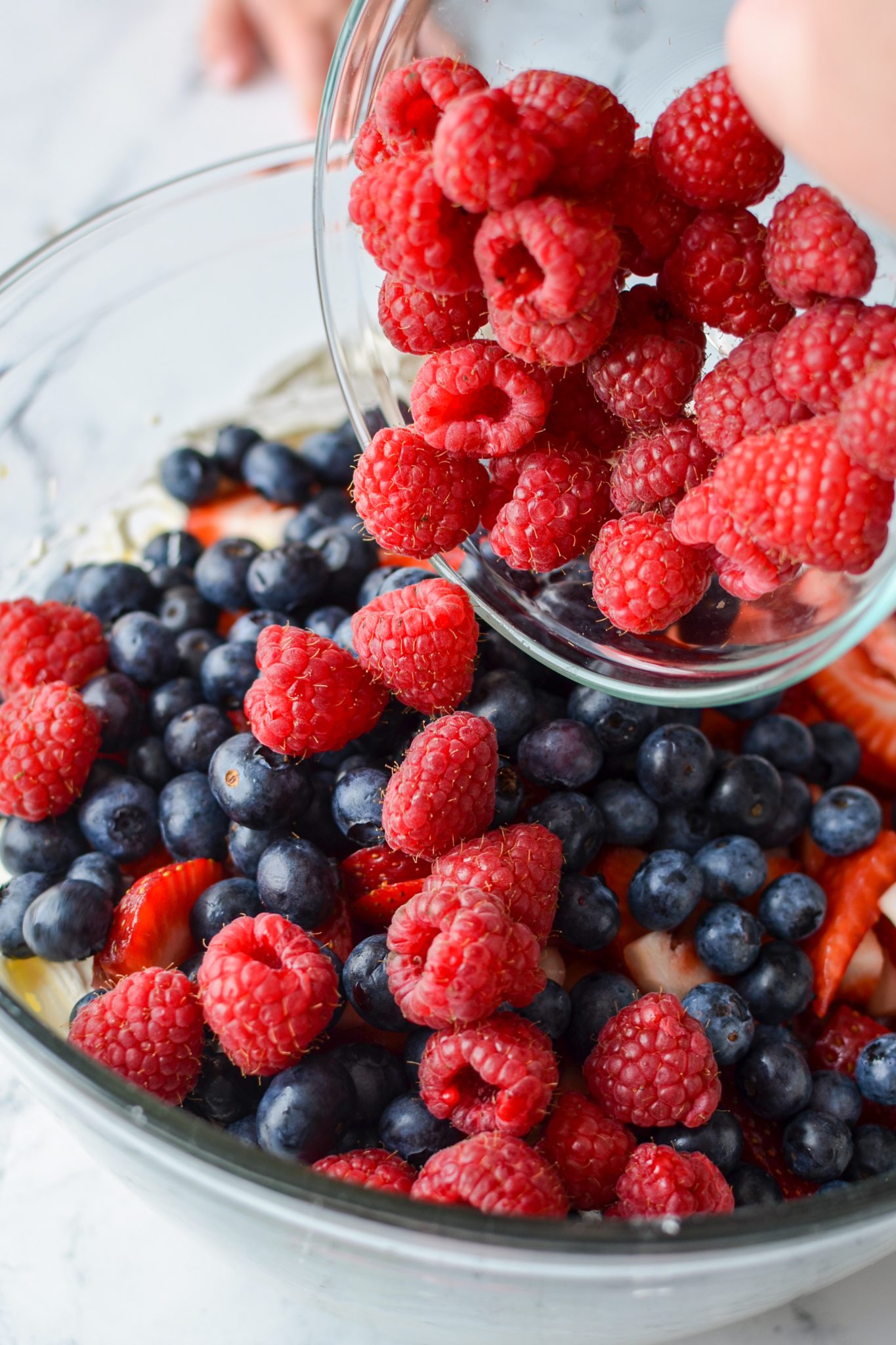 Adding fresh berries to a bowl.