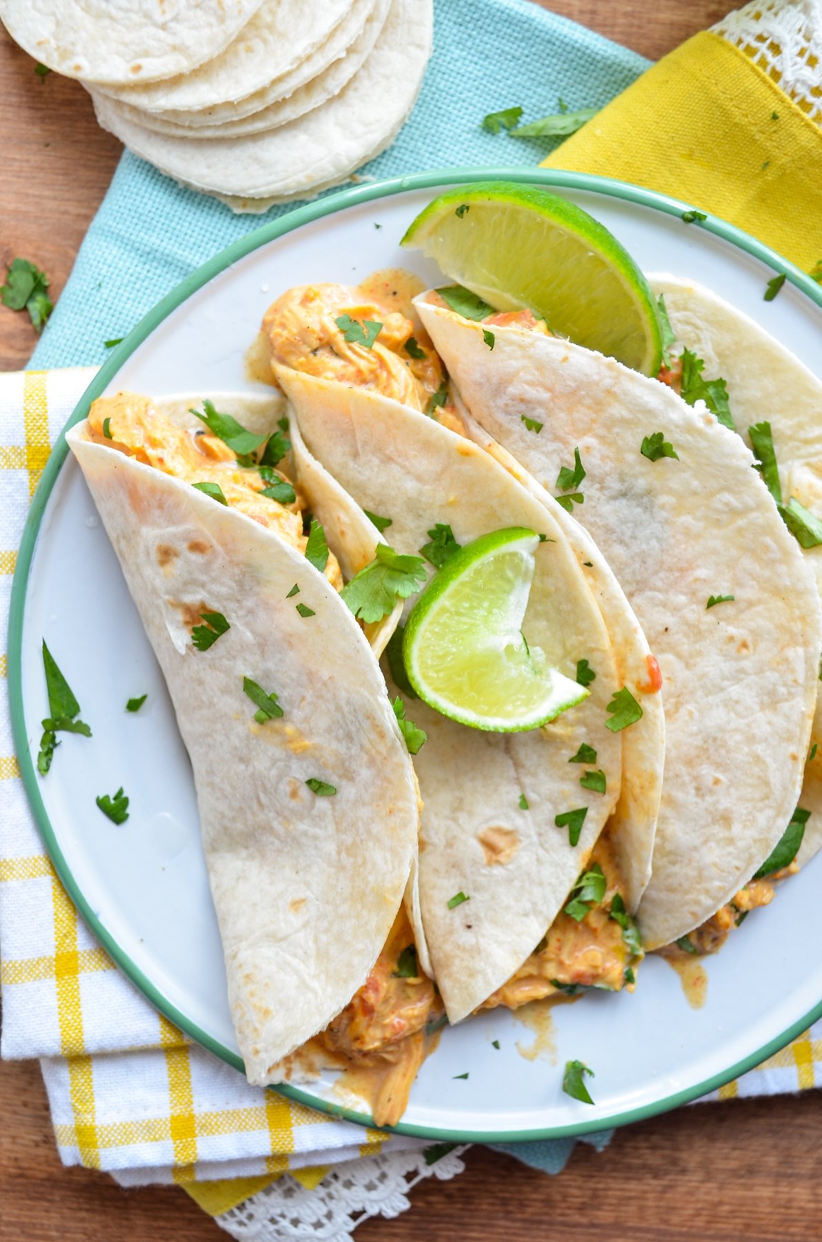 Three chicken queso tacos on a plate, resting on bright napkins.