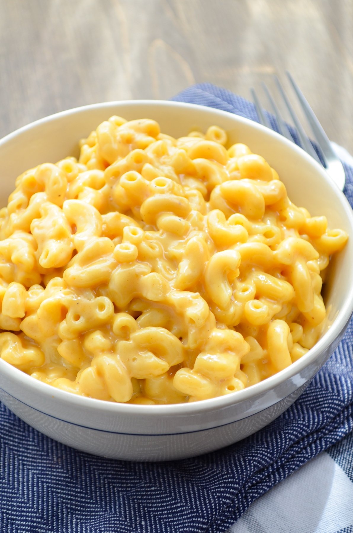 A bowl of macaroni and cheese, resting on blue napkins.