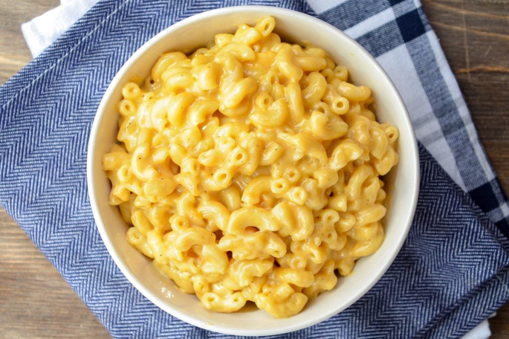 A bowl of Instant Pot macaroni and cheese, on a blue napkin background.