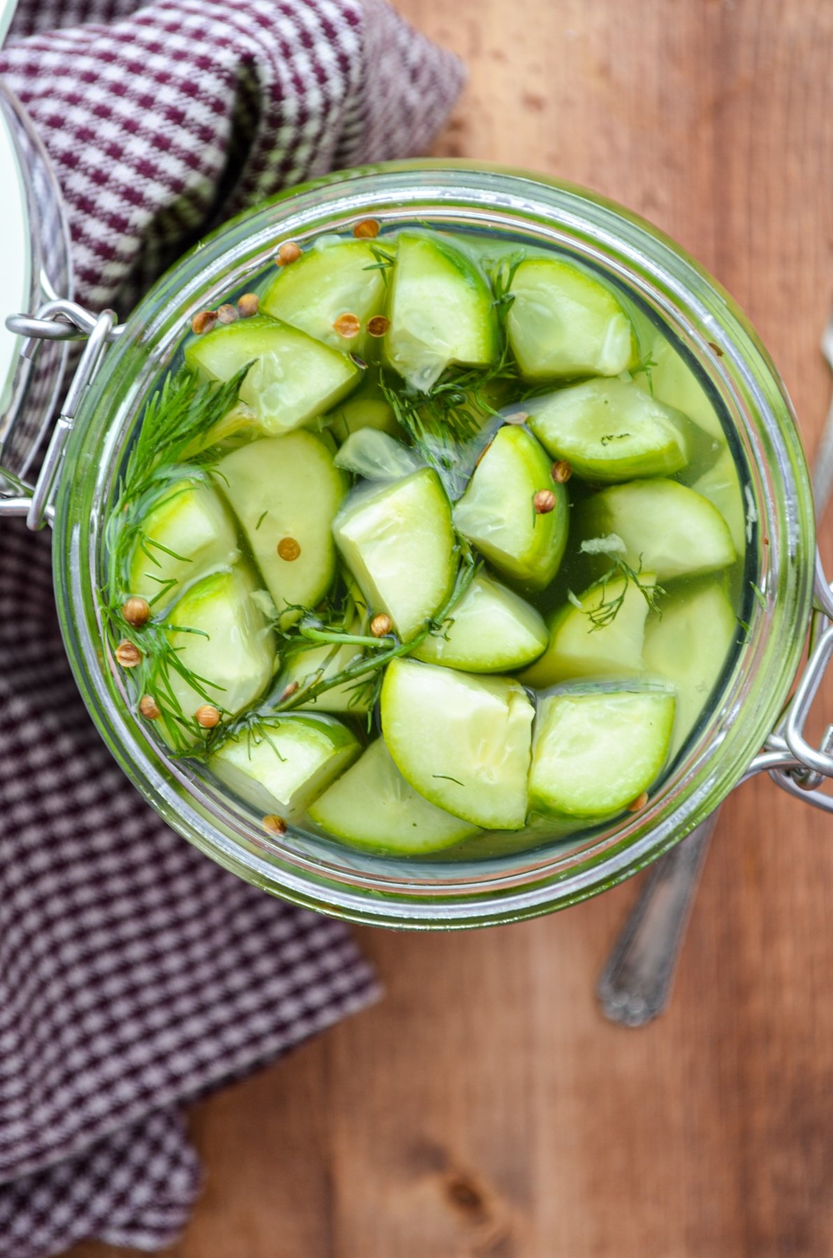 A jar of refrigerator pickles resting on a gingham napkin.