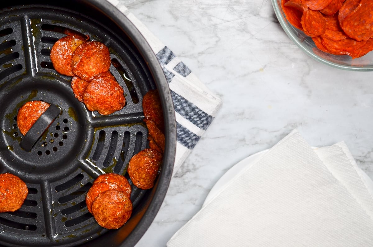 Air fryer pepperoni chips, fully cooked and ready to be drained on paper towels.