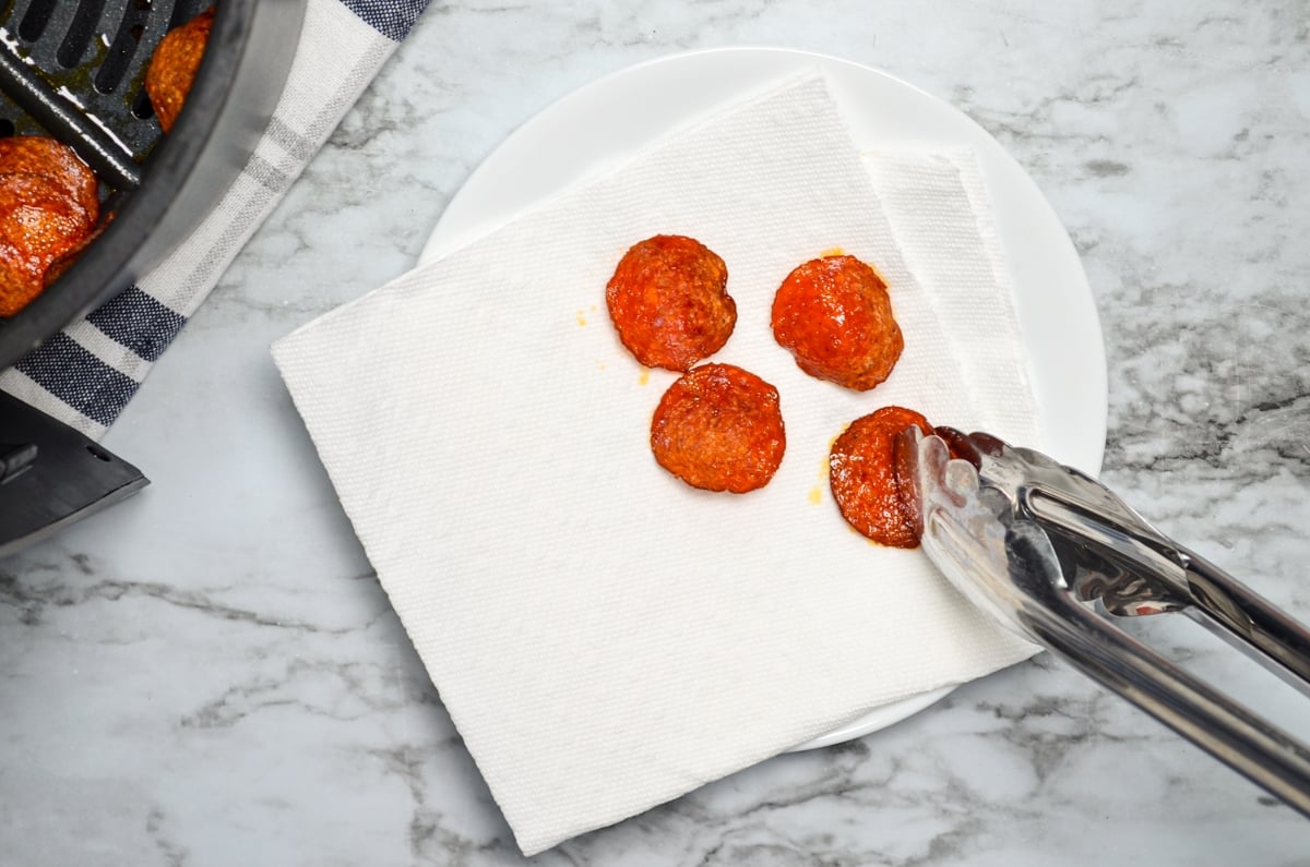 Air fryer pepperoni chips being drained on a double layer of paper towels.