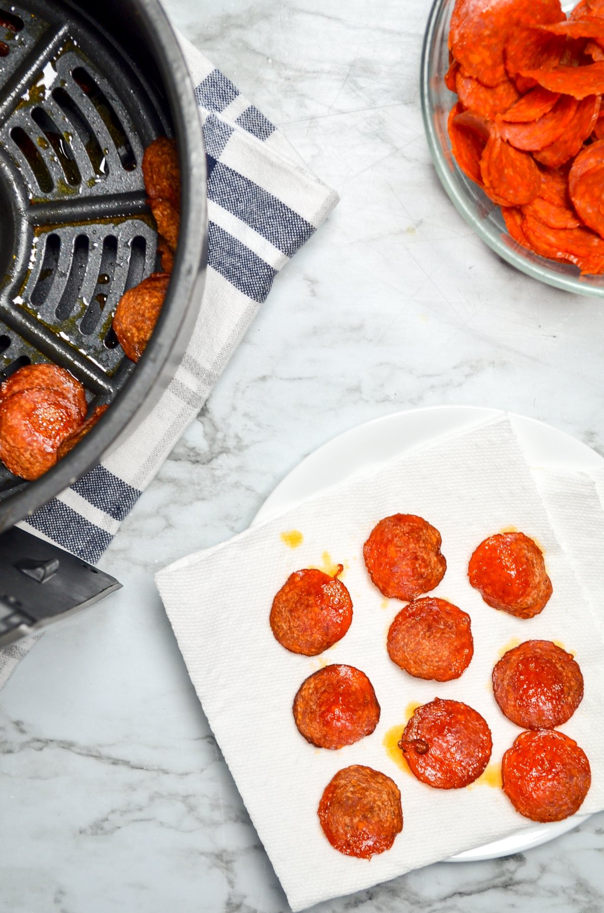 Air fryer pepperoni chips draining on paper towel to remove excess grease.