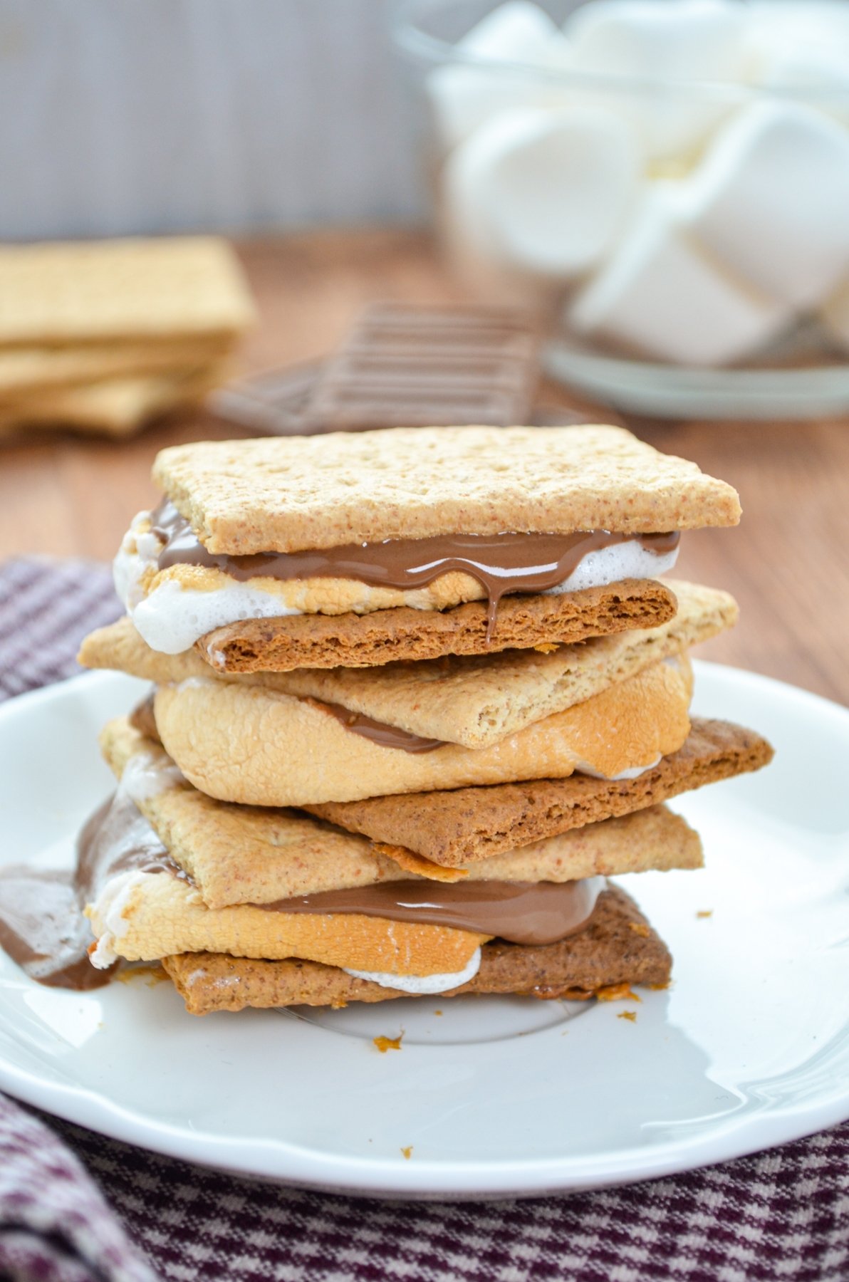 A stack of three smores on a small white plate.