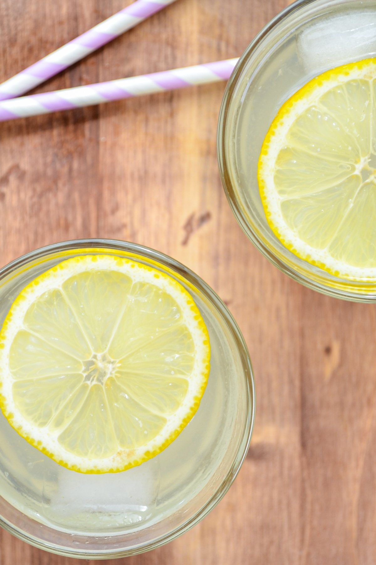 Two glasses of lemonade, garnished with lemon slices.