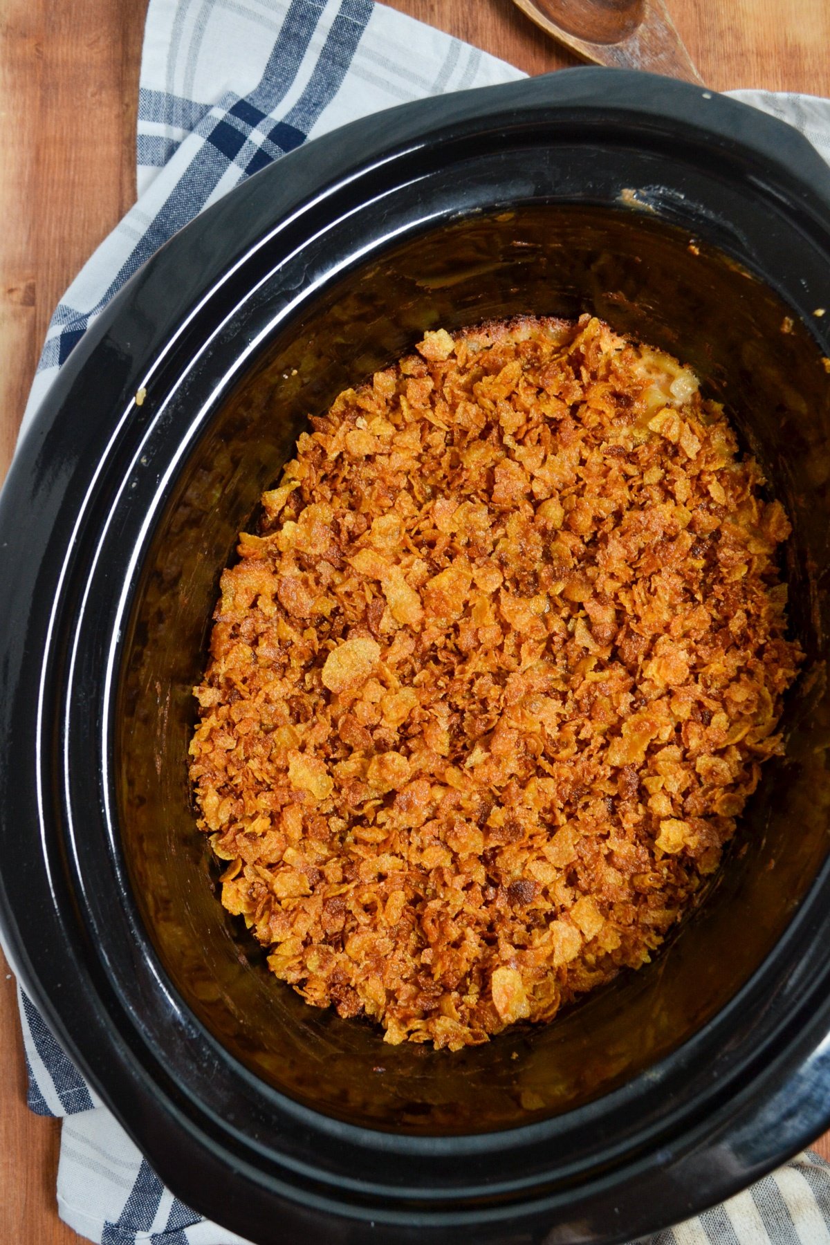 A crock pot of cheesy hashbrown casserole resting on top of a napkin.