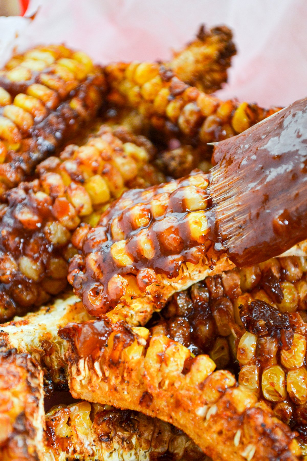 Air fryer corn ribs being brushed with barbeque sauce.