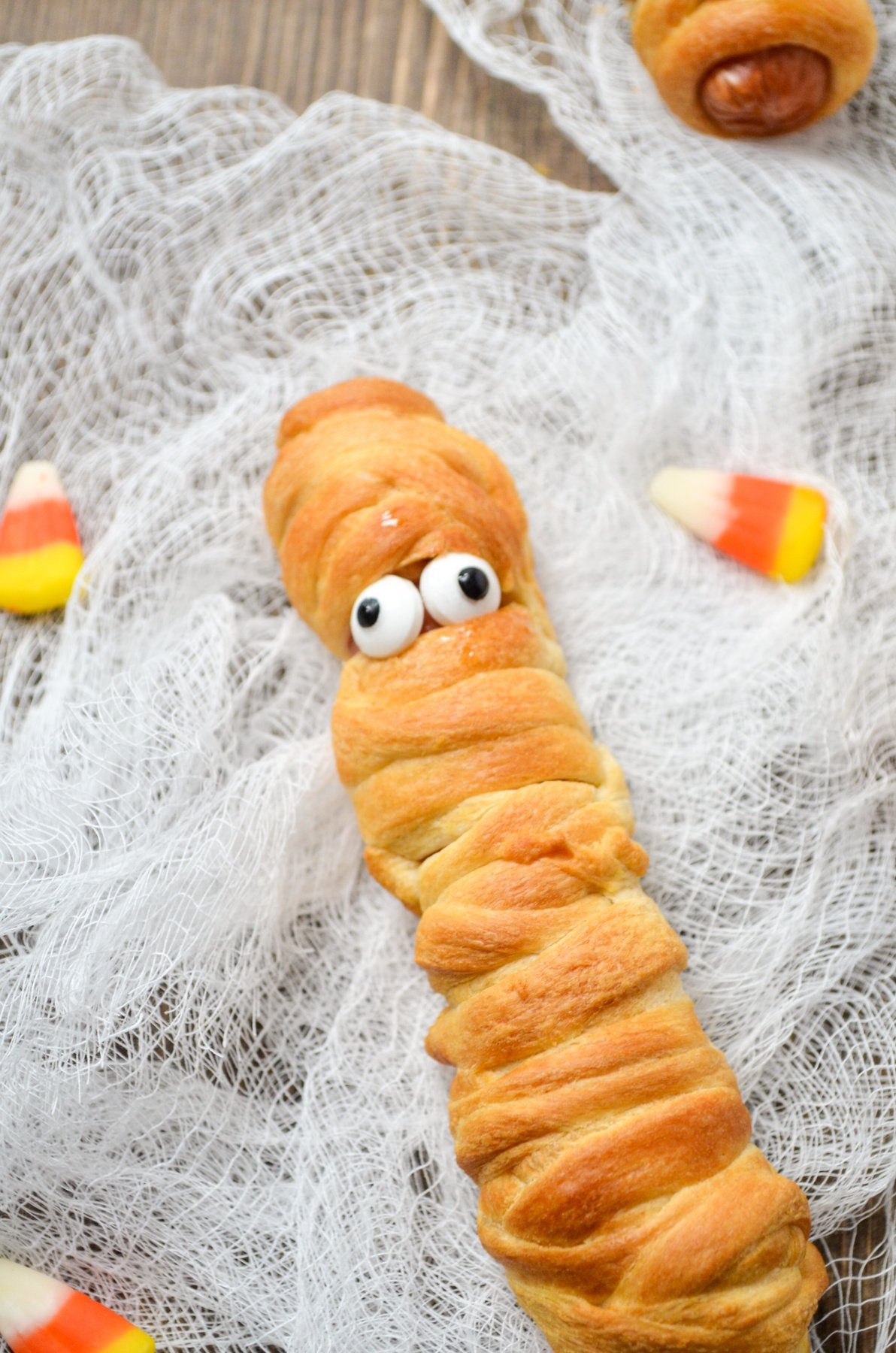 A hot dog wrapped in crescent roll dough, fitted with candy eyes.