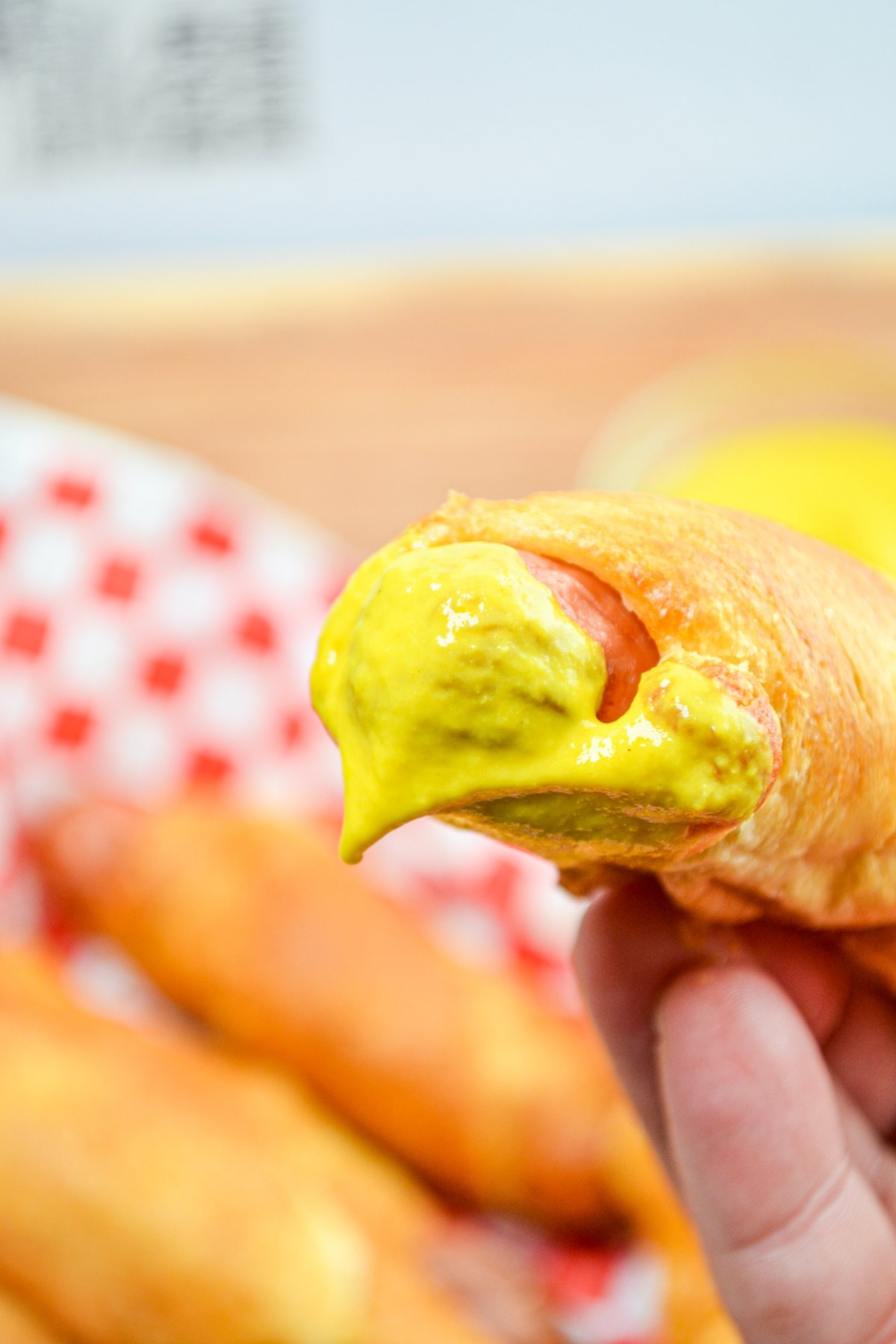 A pig in a blanket, dipped in bright yellow mustard.