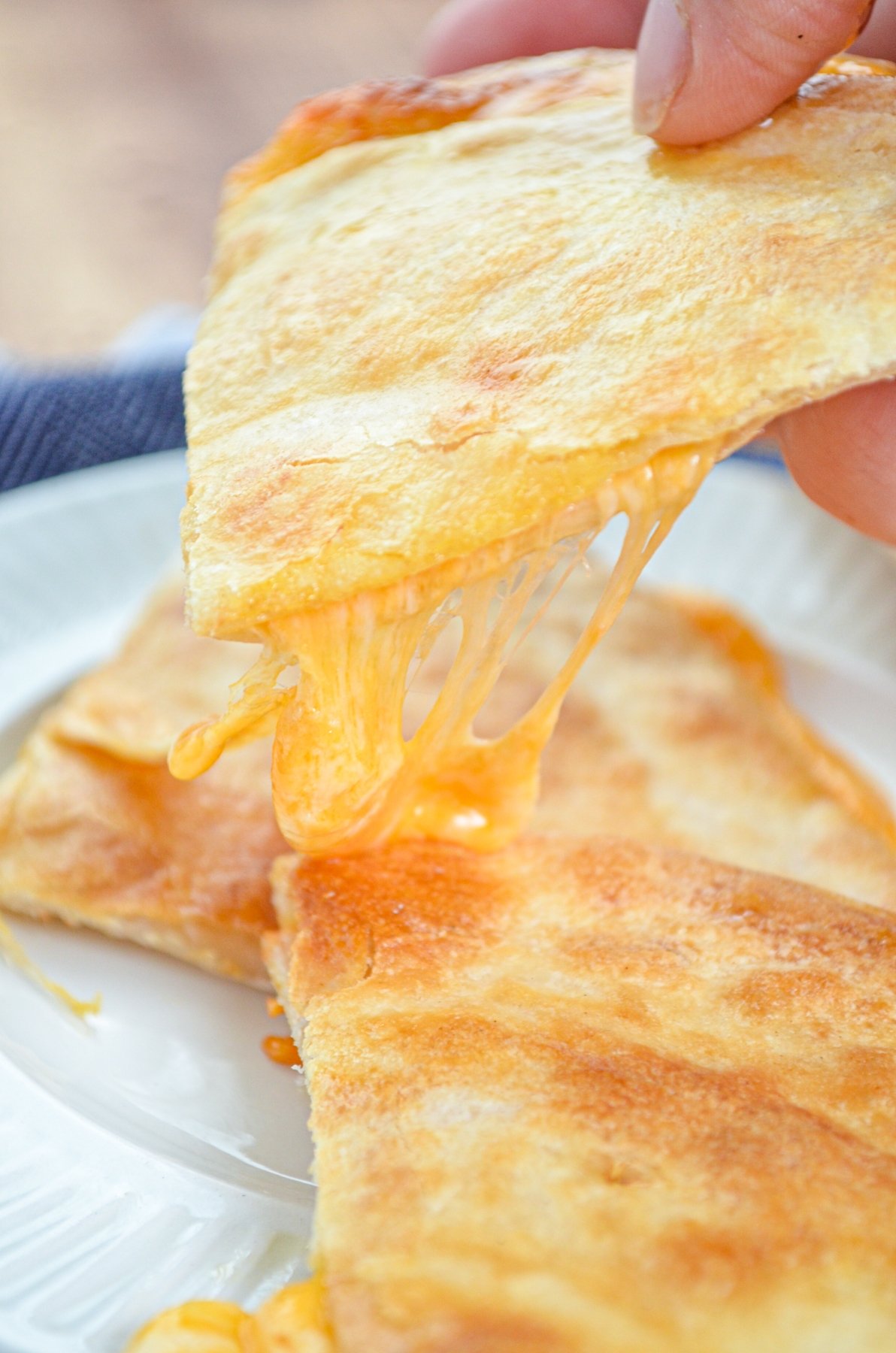 A stack of cheese quesadillas, a triangle being lifted with cheese stretching.