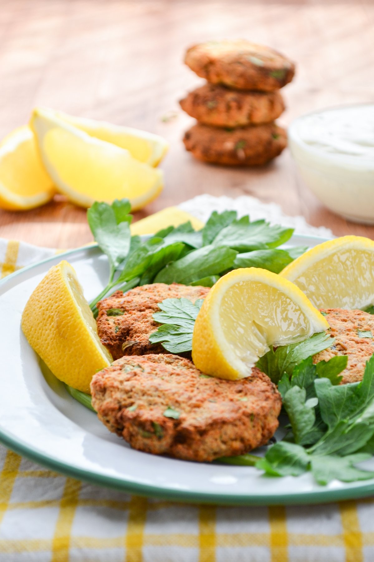 Salmon patties, served on a plate and garnished with fresh parsley and lemon wedges.