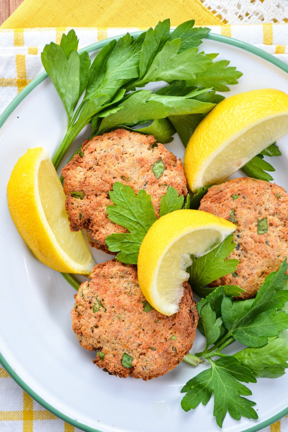 Salmon patties served on a plate, garnished with parsley and lemon.