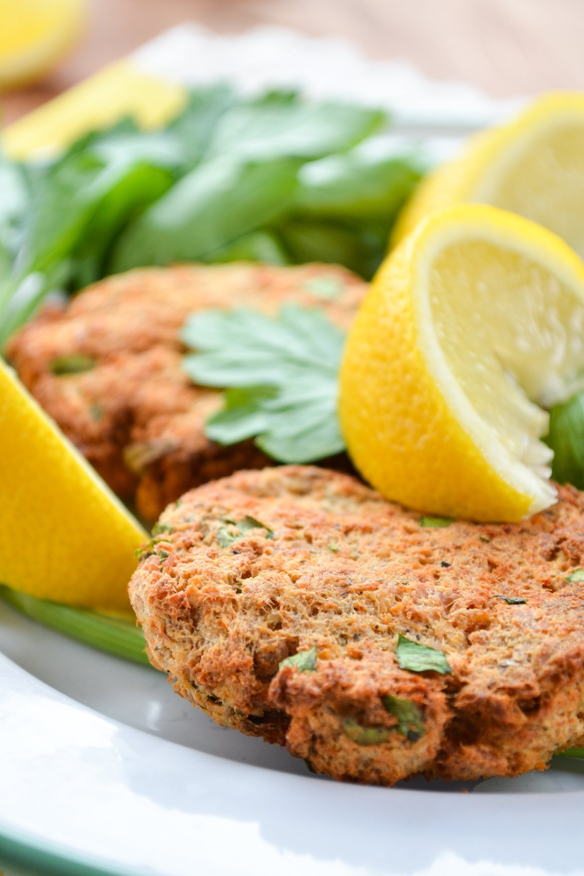 A plate of salmon patties, garnished with parsley and lemon wedges.