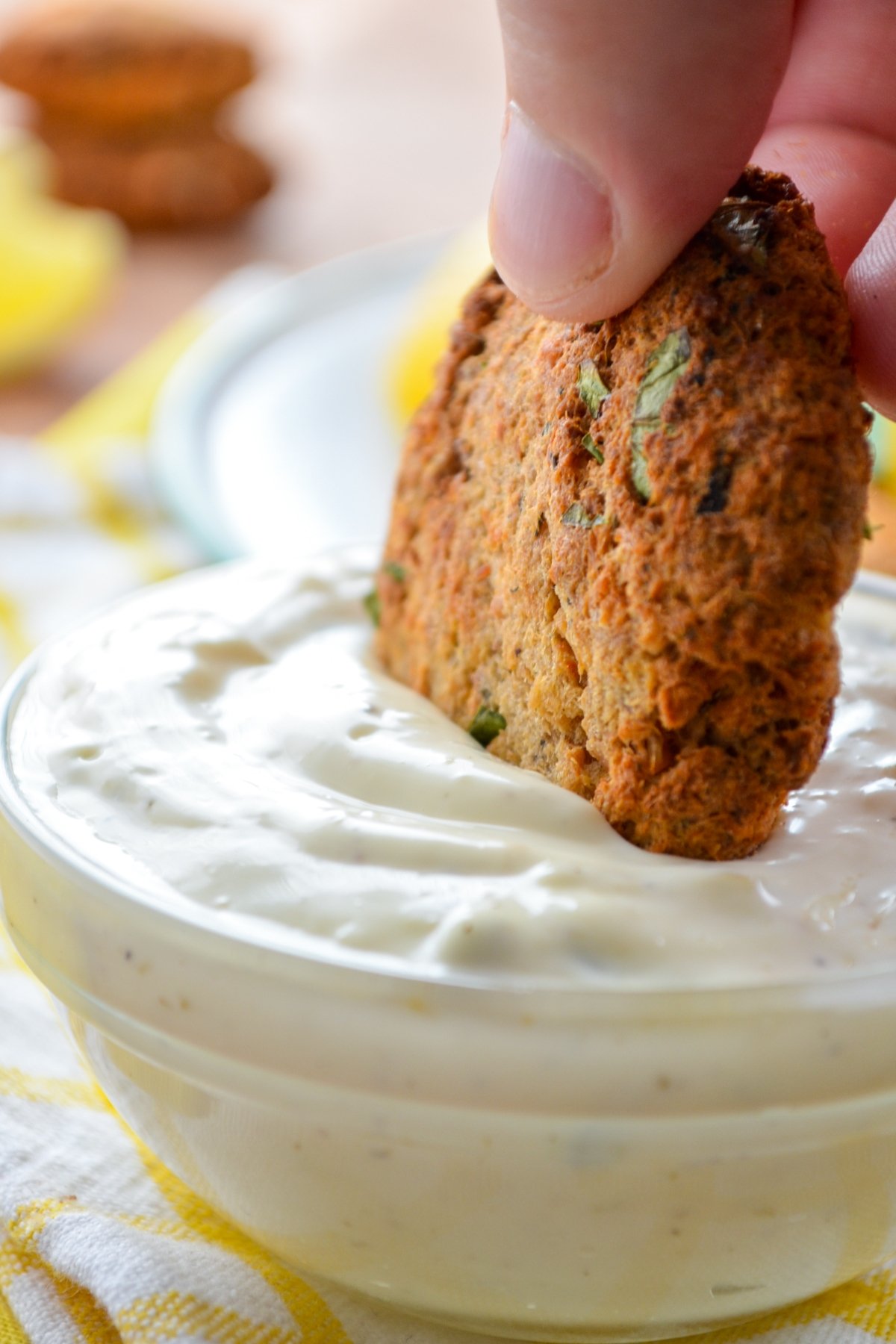 A salmon cake being dipped into a homemade tartar sauce.