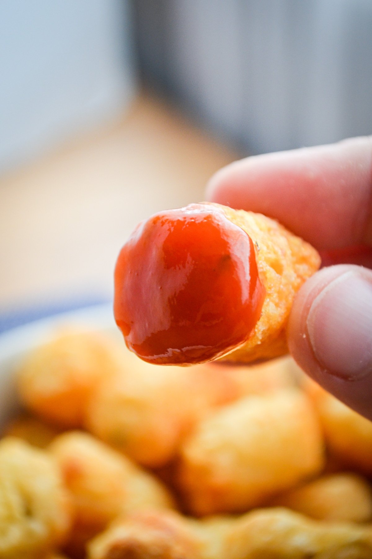 A tater tot being dipped in ketchup.
