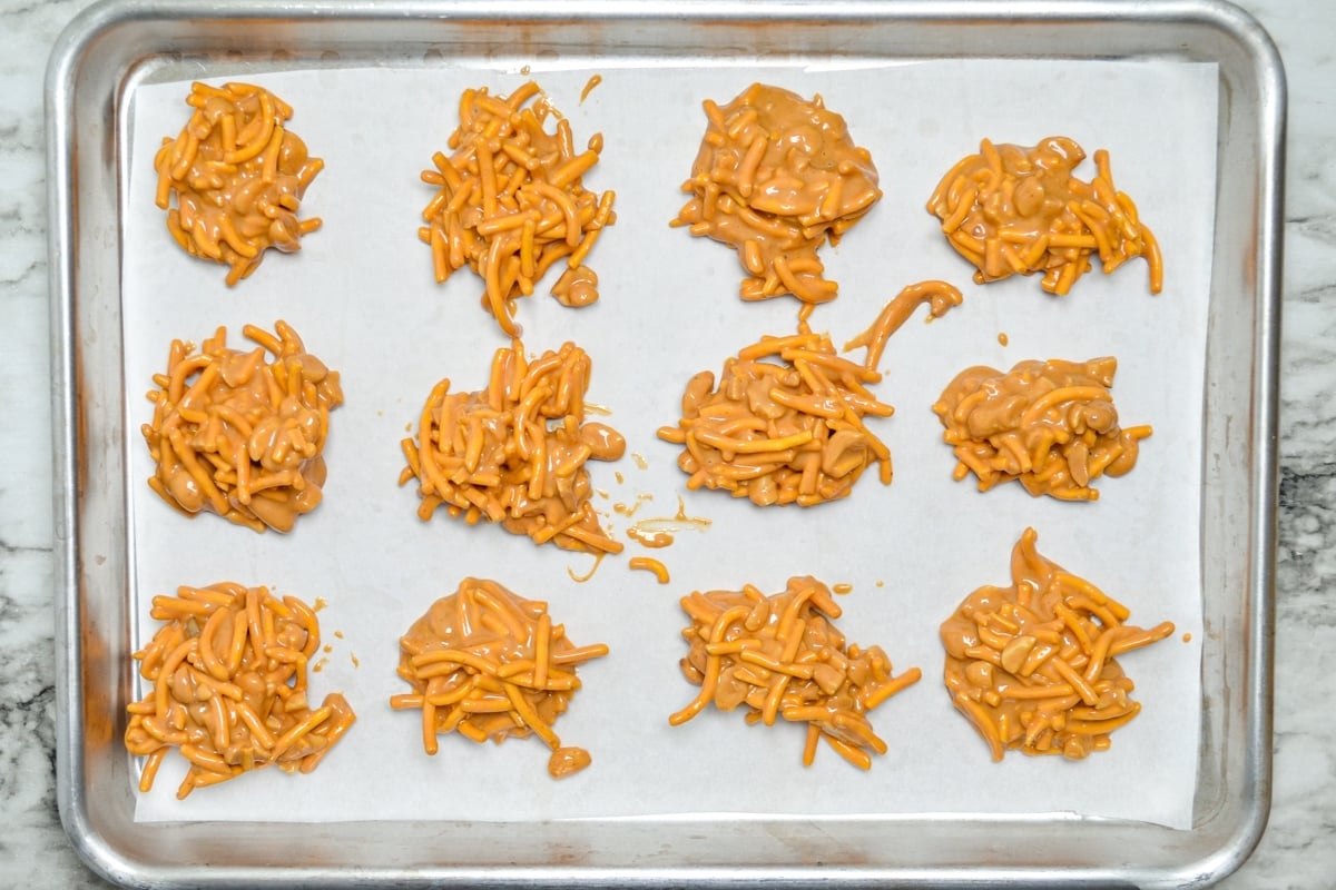 A sheet pan of butterscotch haystack cookies, lined with parchment paper.