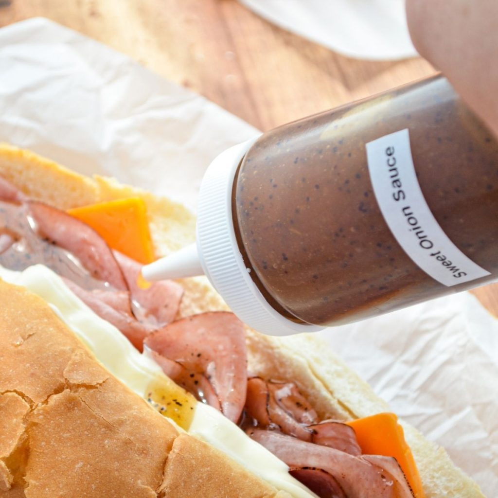 A bottle of sweet onion sauce, being added to a homemade sub.