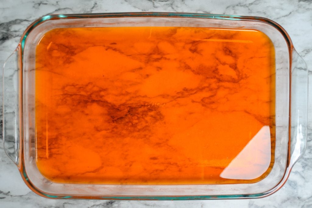 Orange jello layered in the bottom of a glass dish.