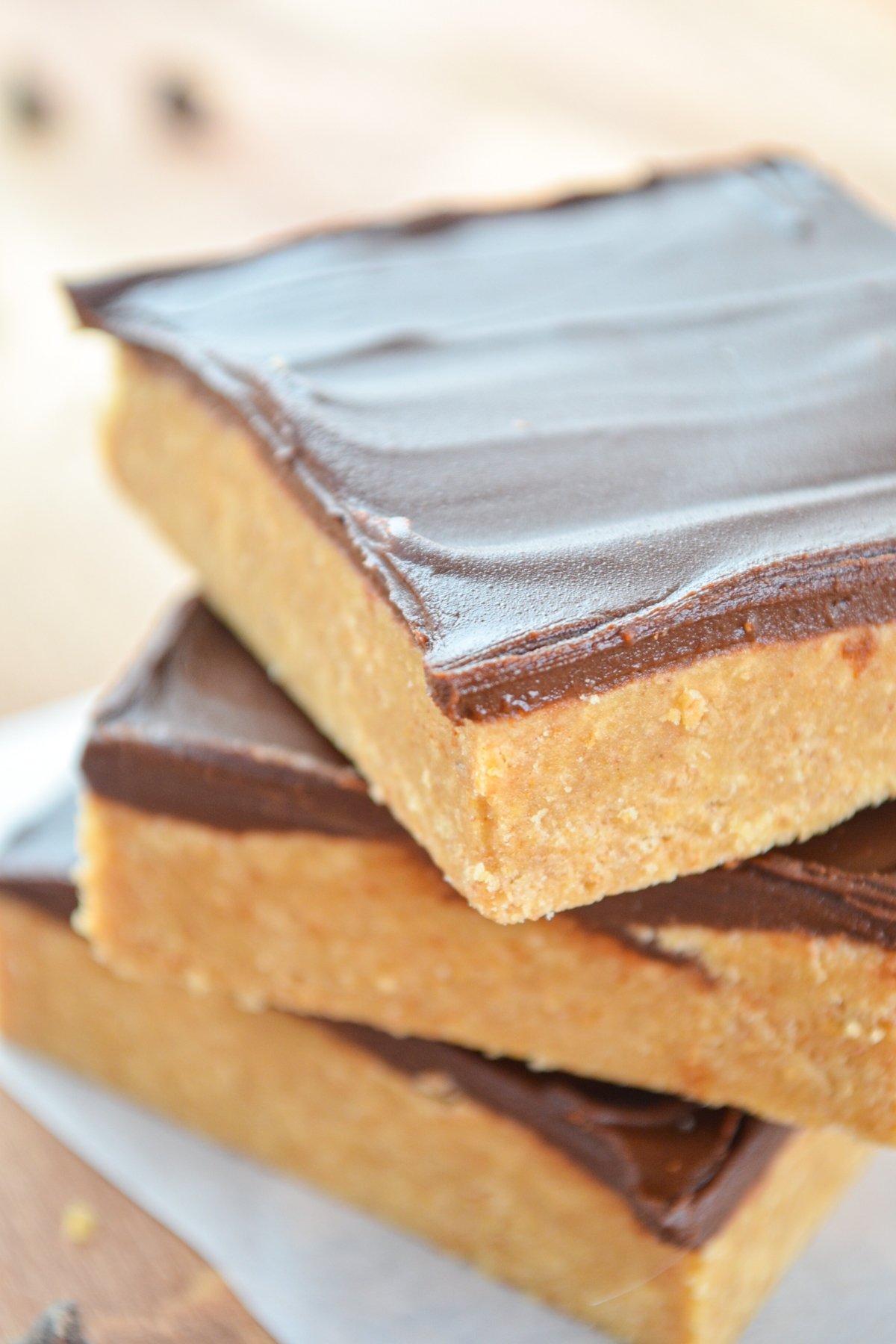 A stack of three peanut butter no bake bars with chocolate topping.