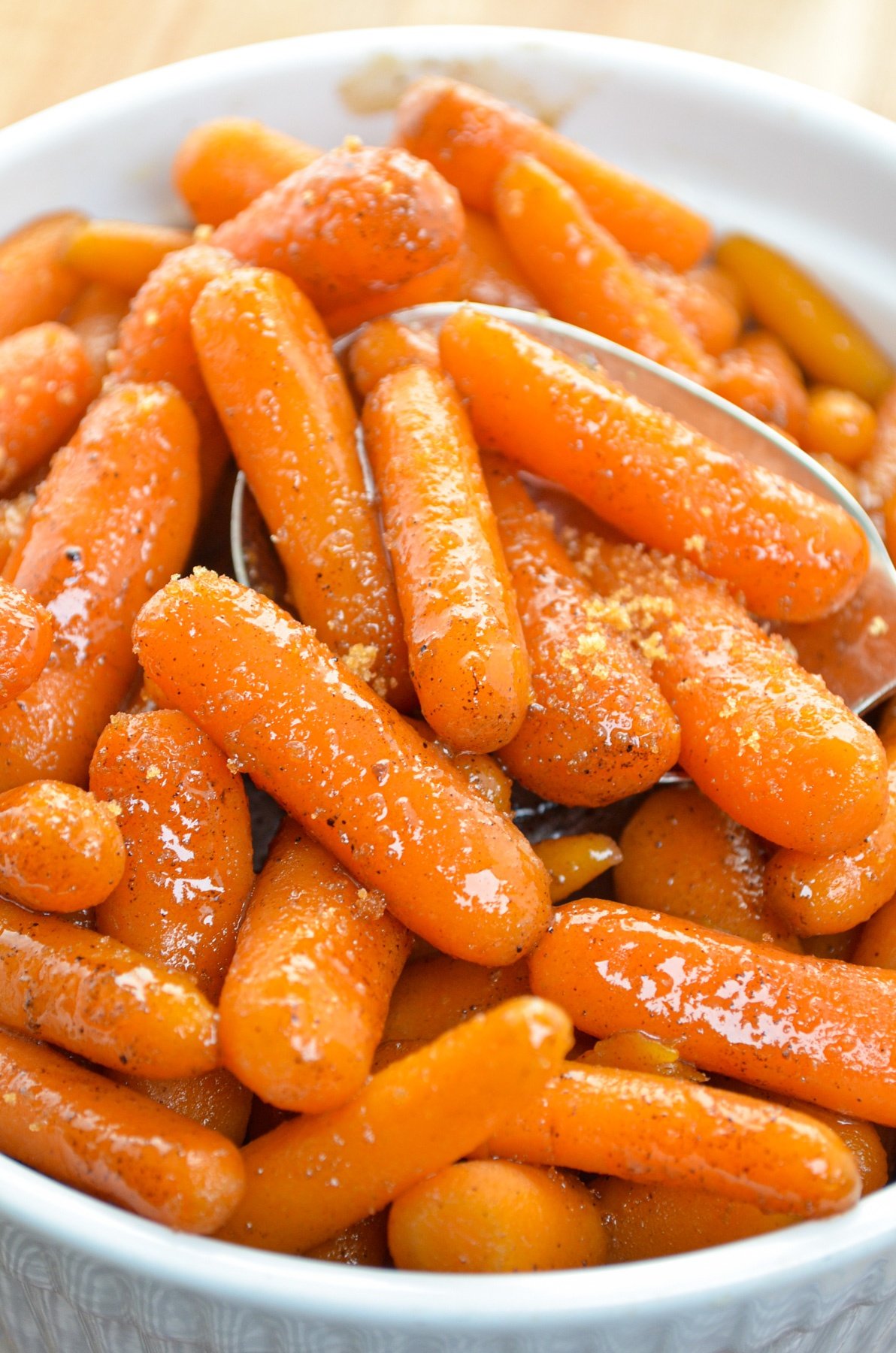 A white serving dish with maple glazed carrots in it. Sprinkled with brown sugar.