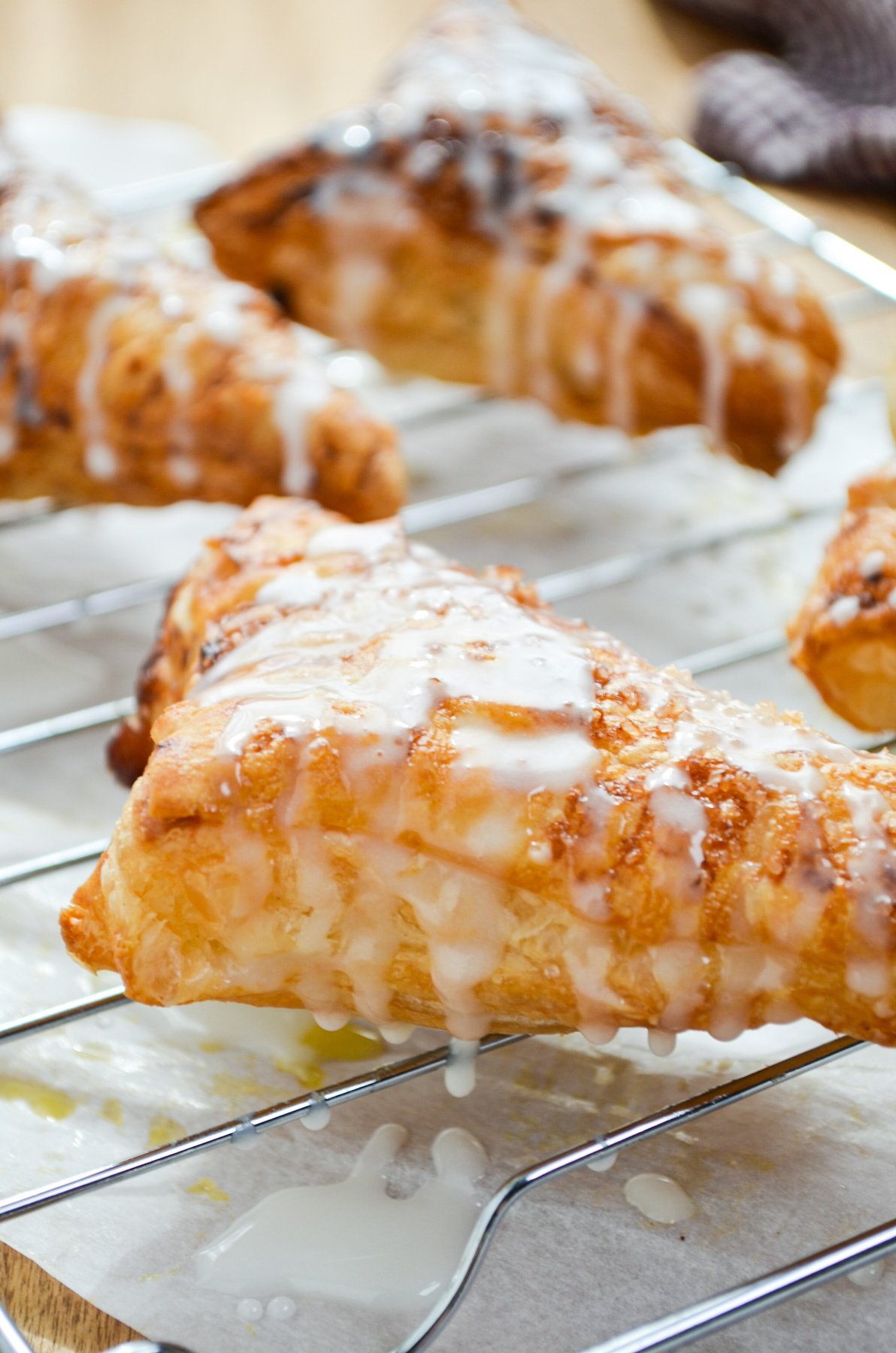 Apple turnovers on a cooling rack, drizzled with glaze.
