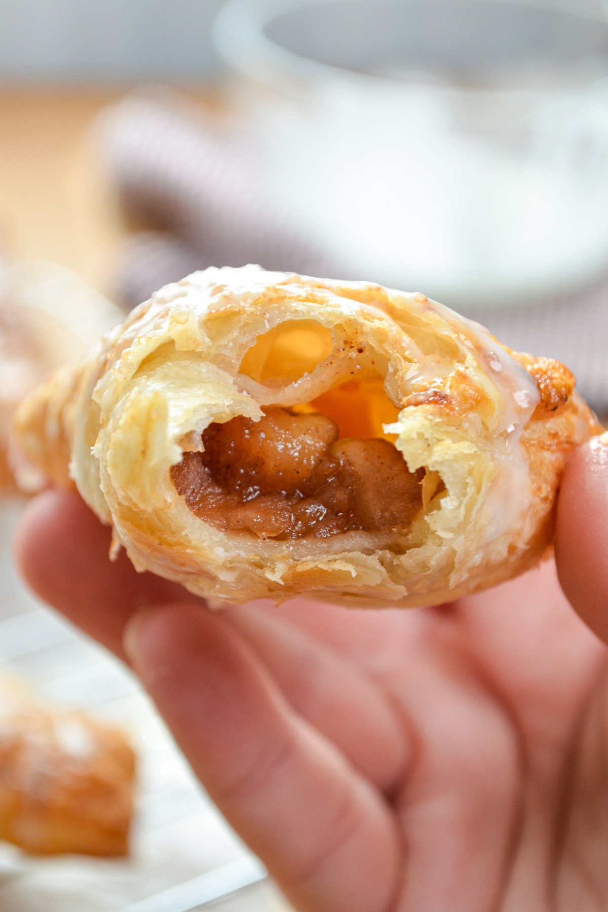 An apple turnover, with a bite taken out of it, exposing the apple filling.