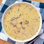 A bowl of homemade mushroom soup on a blue check napkin