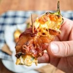 A hand holding up a homemade bacon wrapped jalapeno popper