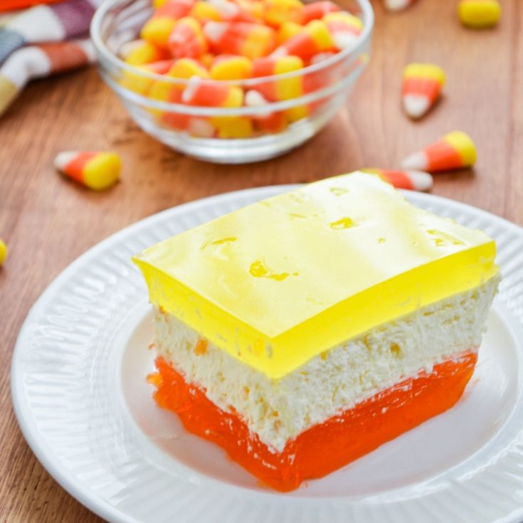 A jello dessert with three layers, using Halloween inspired colors. Orange, yellow, and white layers.