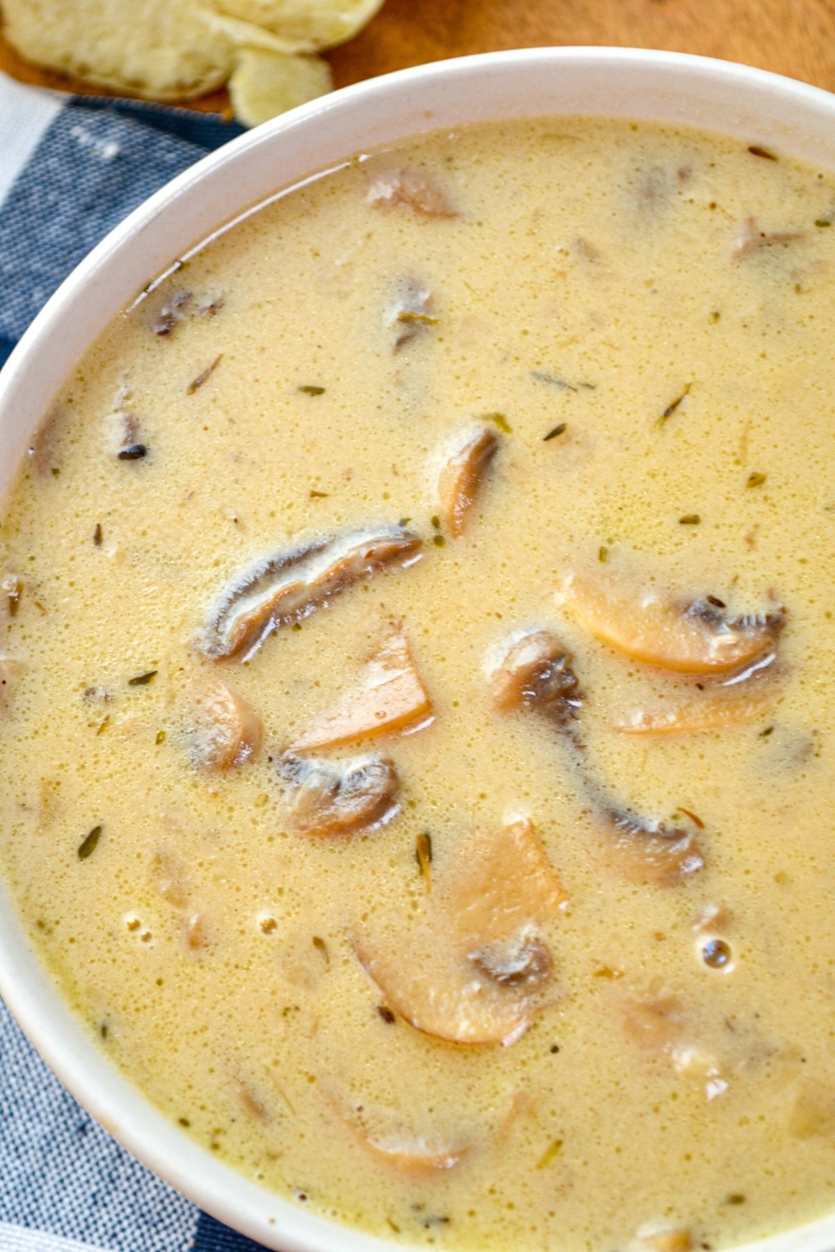 A bowl of cream of mushroom soup, resting on blue check napkins.