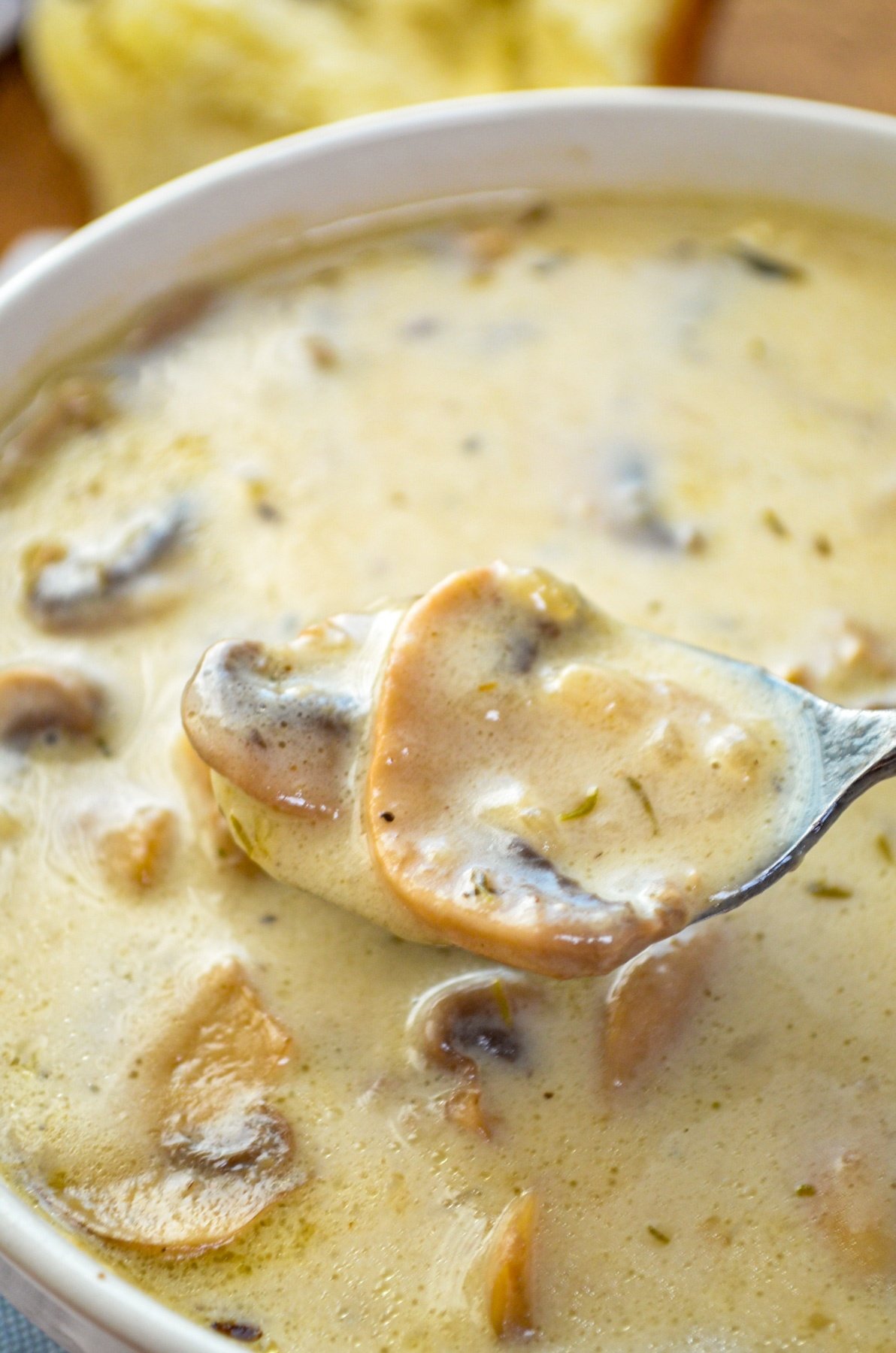 A bowl of mushroom soup with a spoon taking a spoonful.