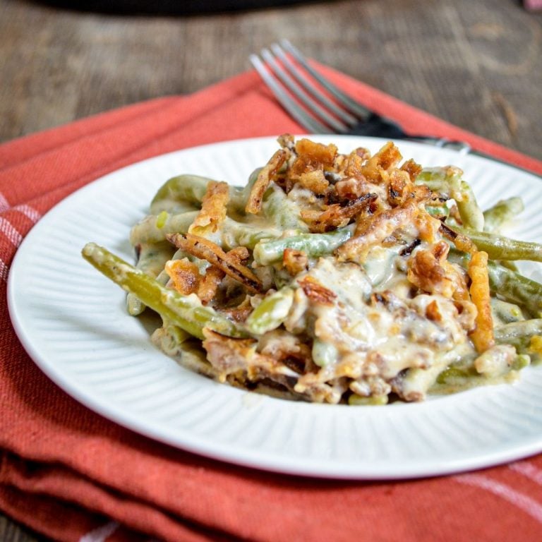 A plate of green bean casserole, served on a small plate on top of cloth napkin.