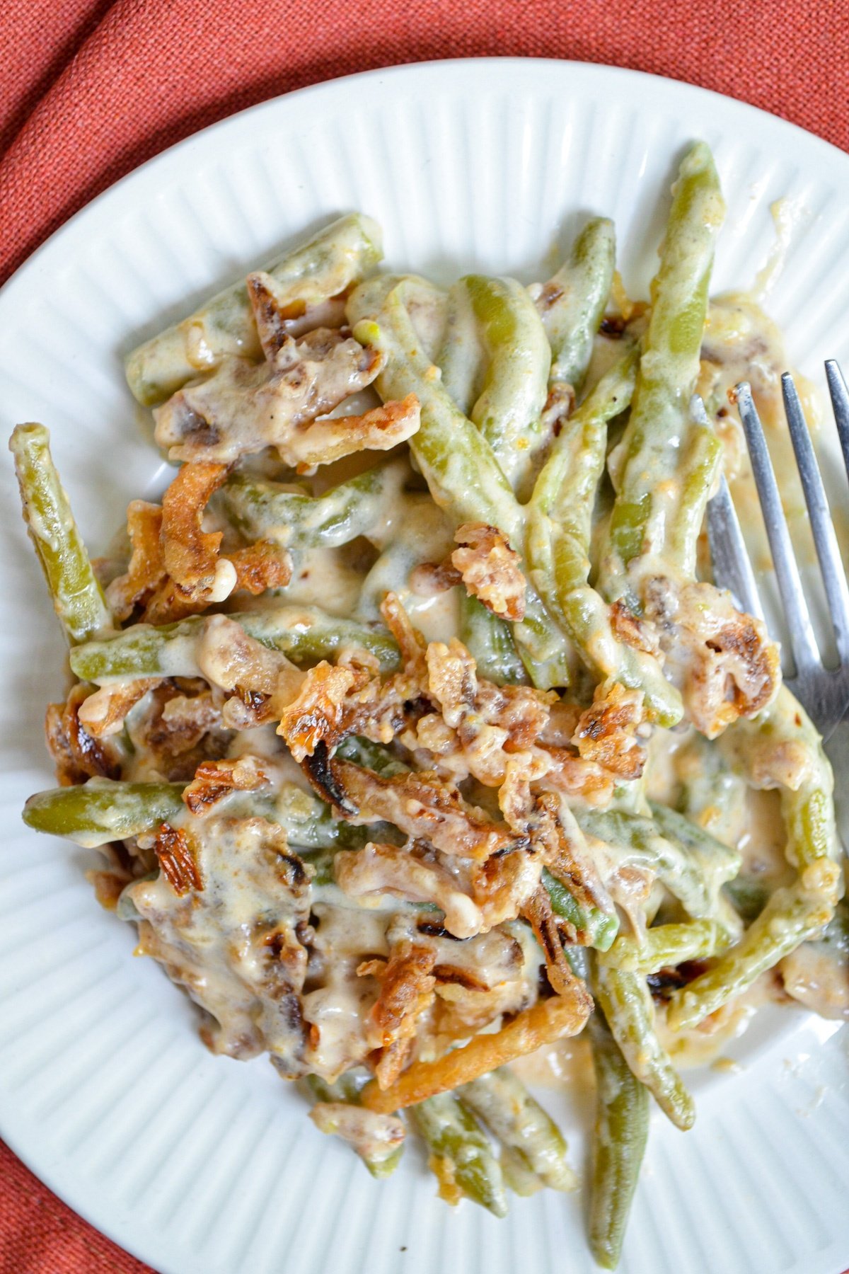 A plate of green bean casserole, topped with french fried onions. 
