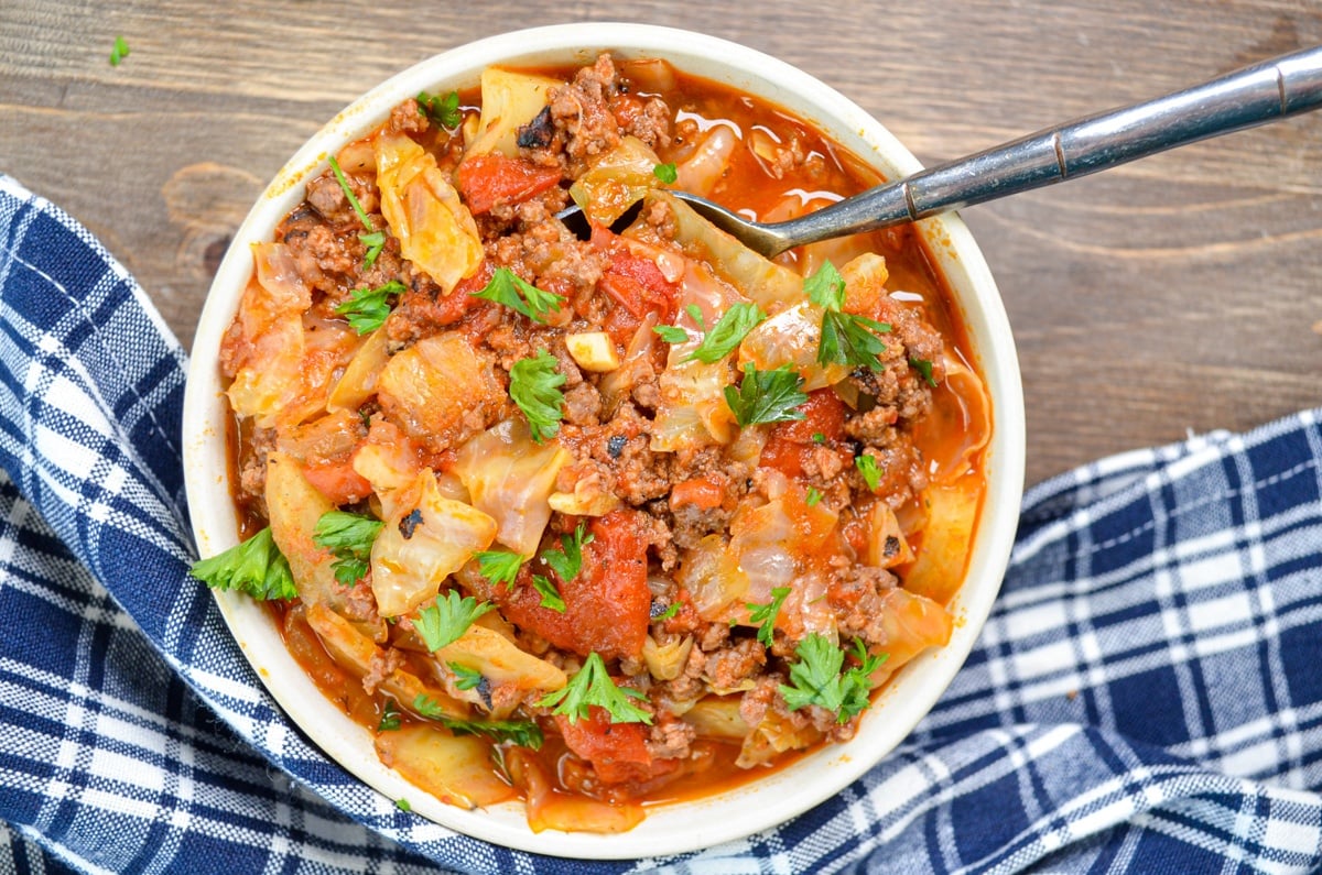 A bowl of unstuffed cabbage roll soup on a wood background.