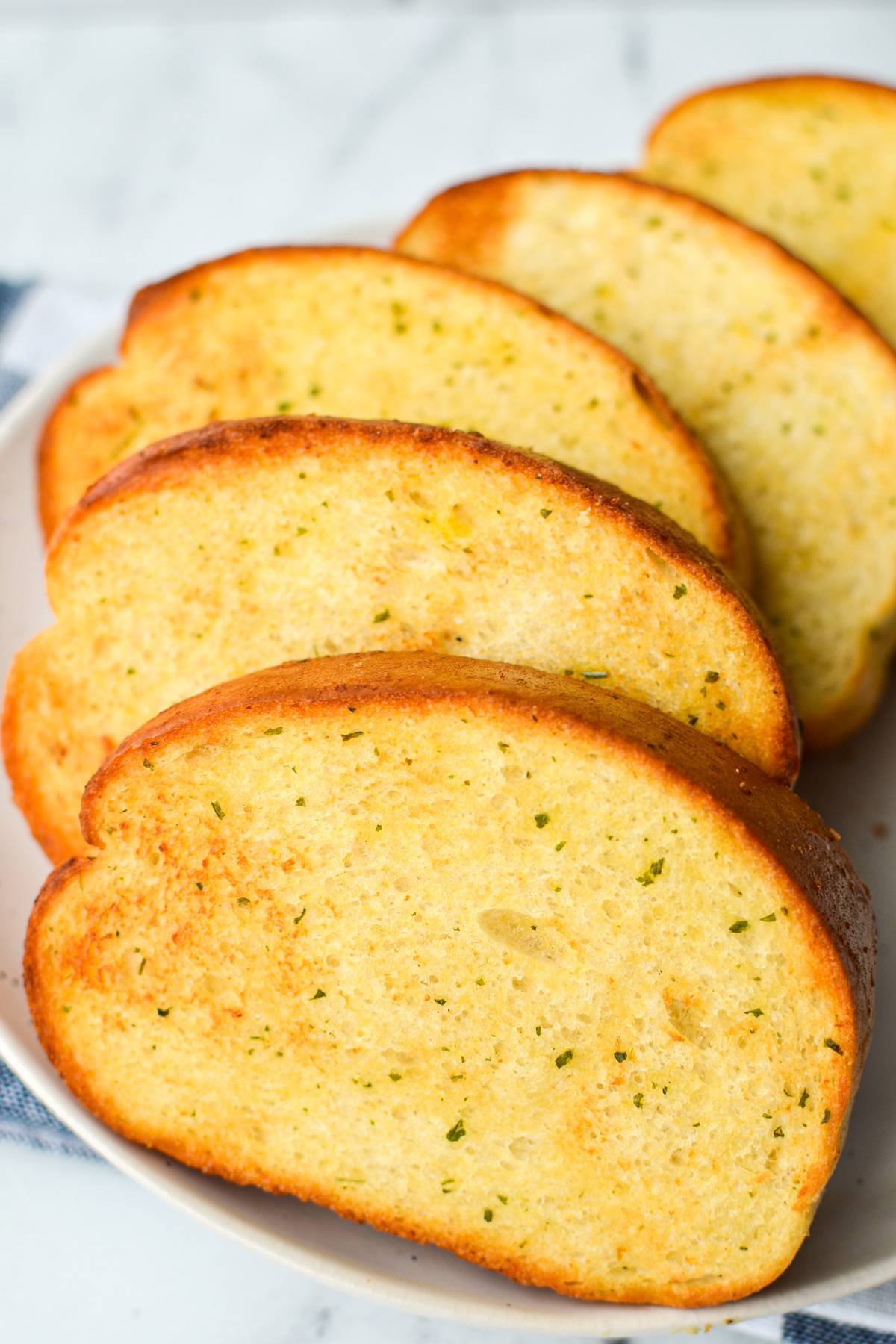 A plate of toasted frozen garlic bread, 5 slices in total.