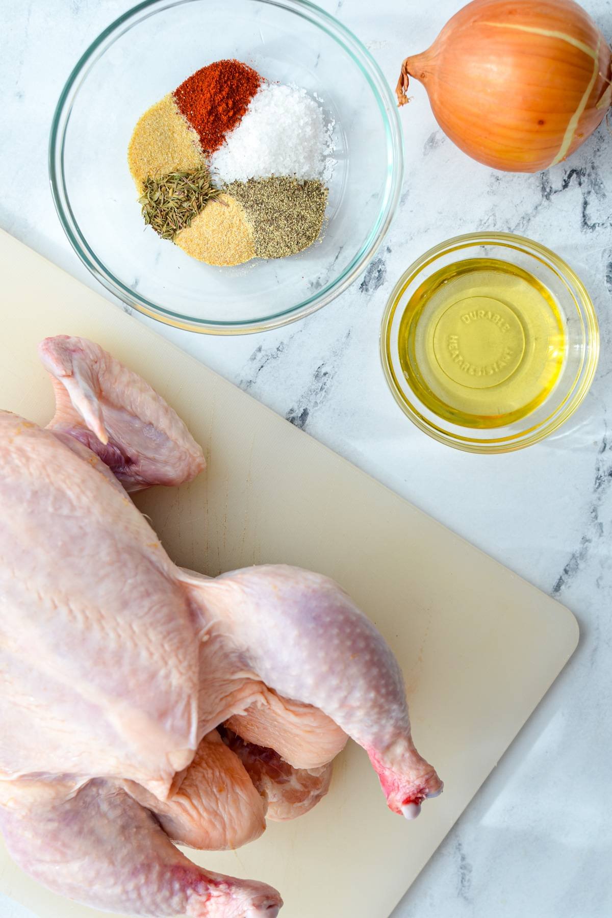 The ingredients needed to make an air fryer whole chicken: chicken, oil, onion, and seasonings.