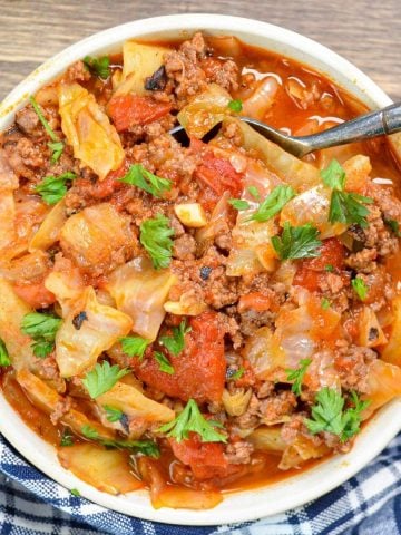 A bowl of cabbage, ground beef, and vegetables, sprinkled with parsley.