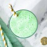 An overhead view of a glass of a green milkshake.