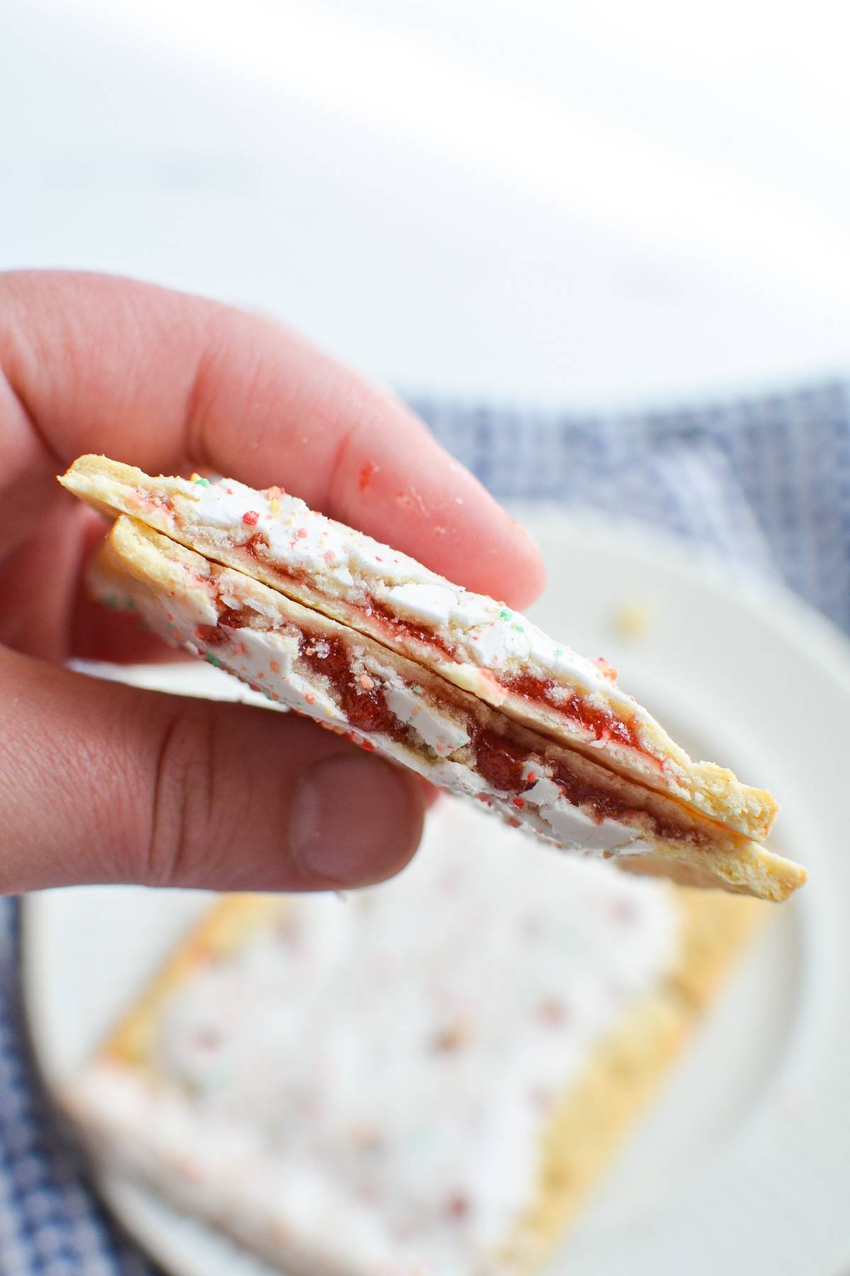 A hand holding pop tarts with a strawberry filling.