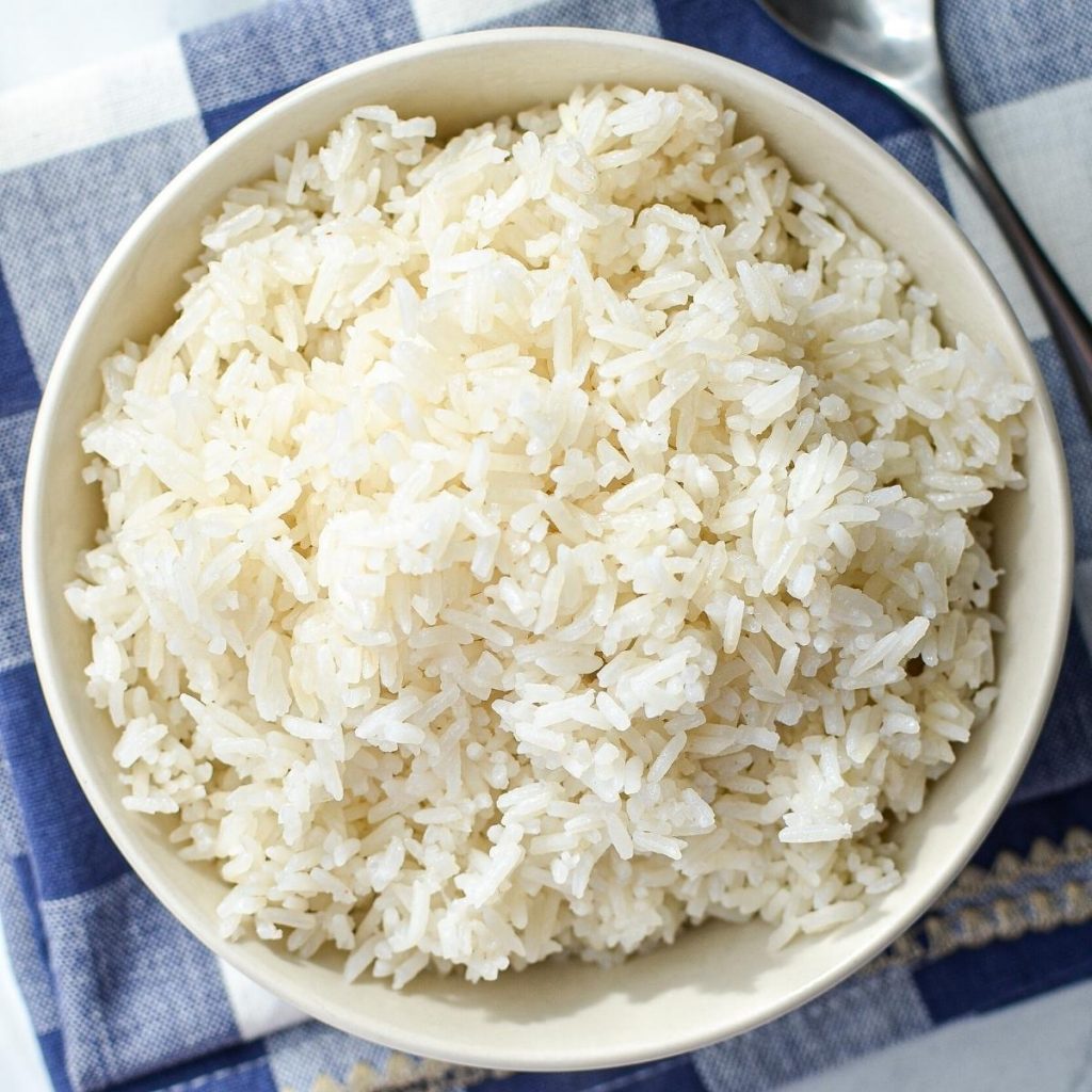 A bowl of white rice on a blue check napkin.