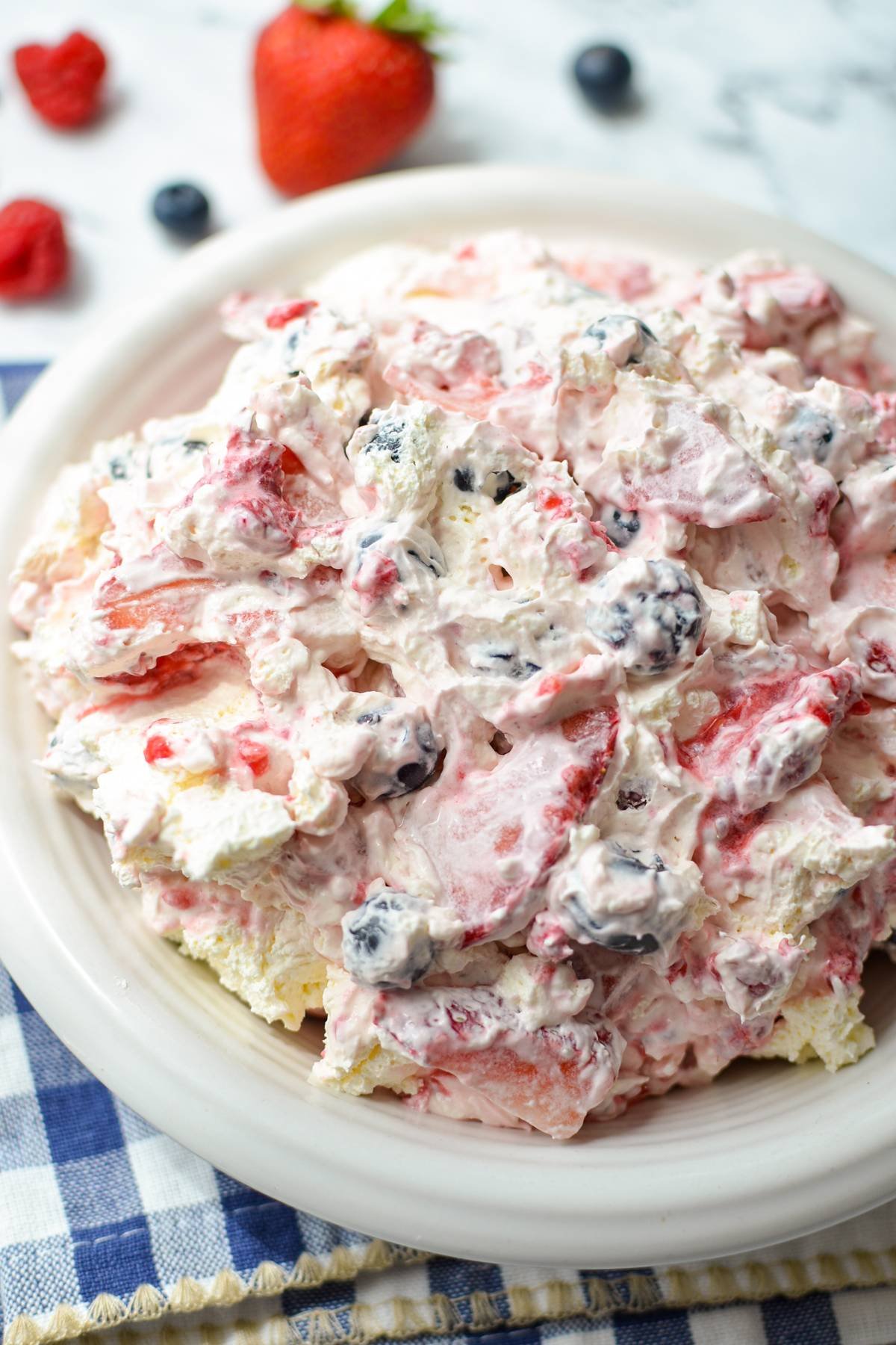 A bowl of whipped cream based salad with fresh berries.