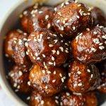 A stack of glazed meatballs, garnished with sesame seeds.